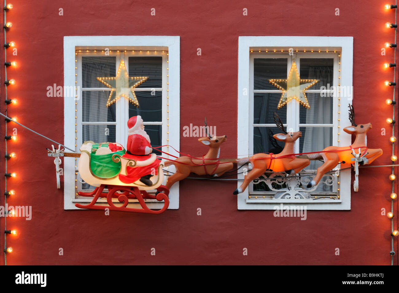 Weihnachtsdekoration, Santa auf Schlitten von Rentieren auf ein rotes Haus mit weißen Krone Glasfenstern gezeichnet Stockfoto