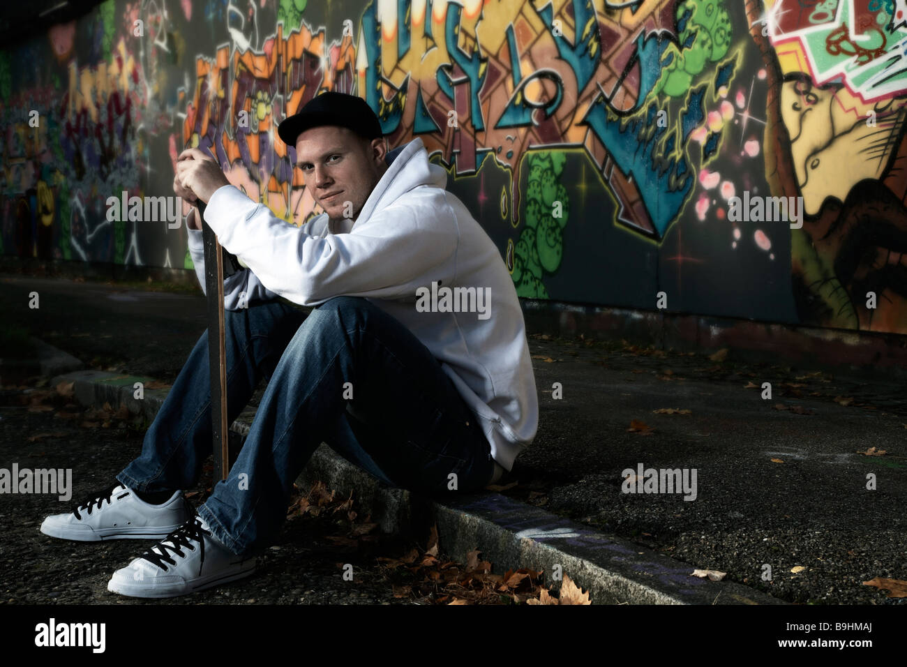 Junger Mann mit einem Skateboard vor einer Graffitiwand Stockfoto