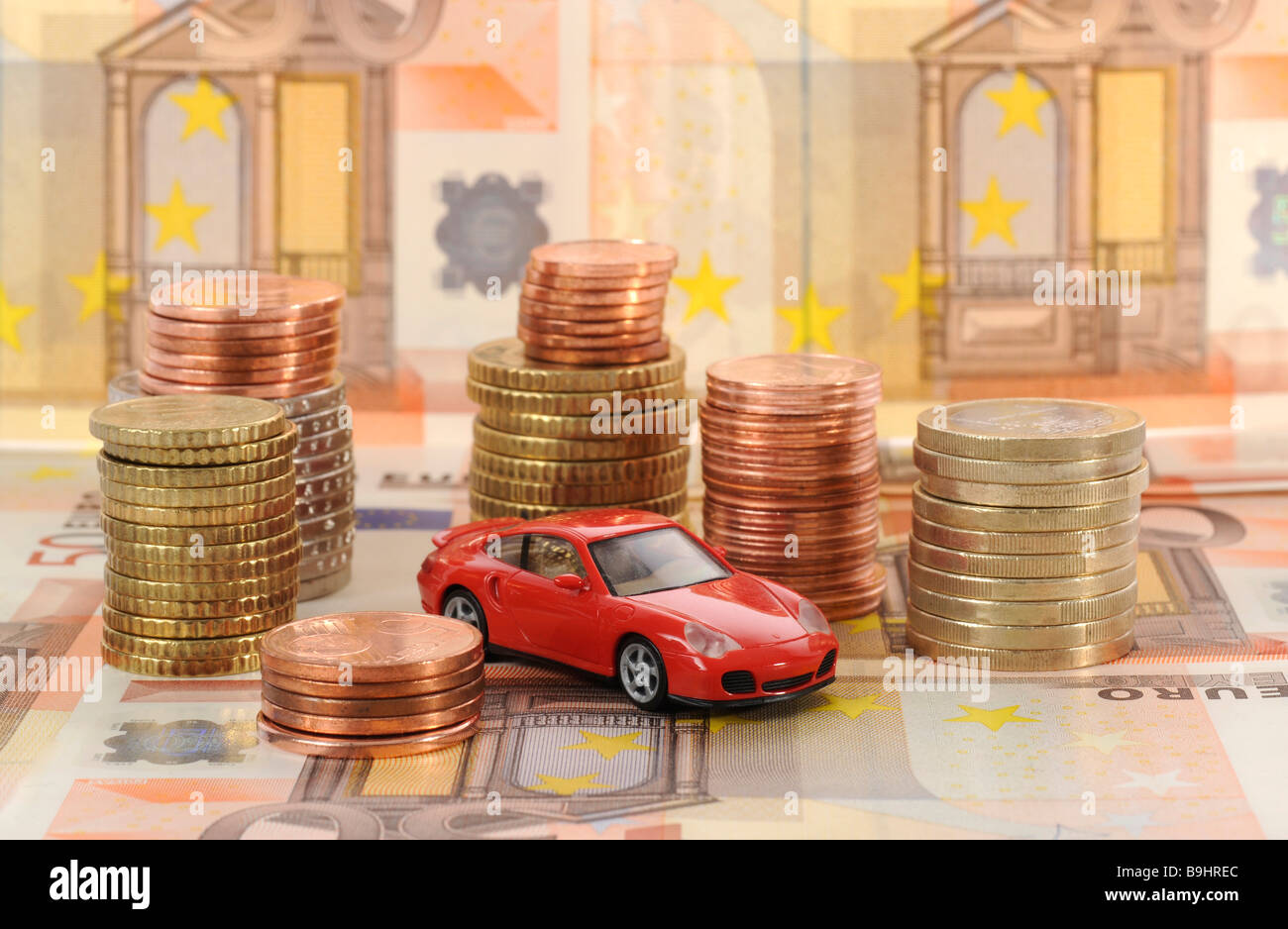 Miniatur-Auto auf Münzen, symbolisch für Pendlerpauschale, Kilometergeld, Wagenpflege Stockfoto