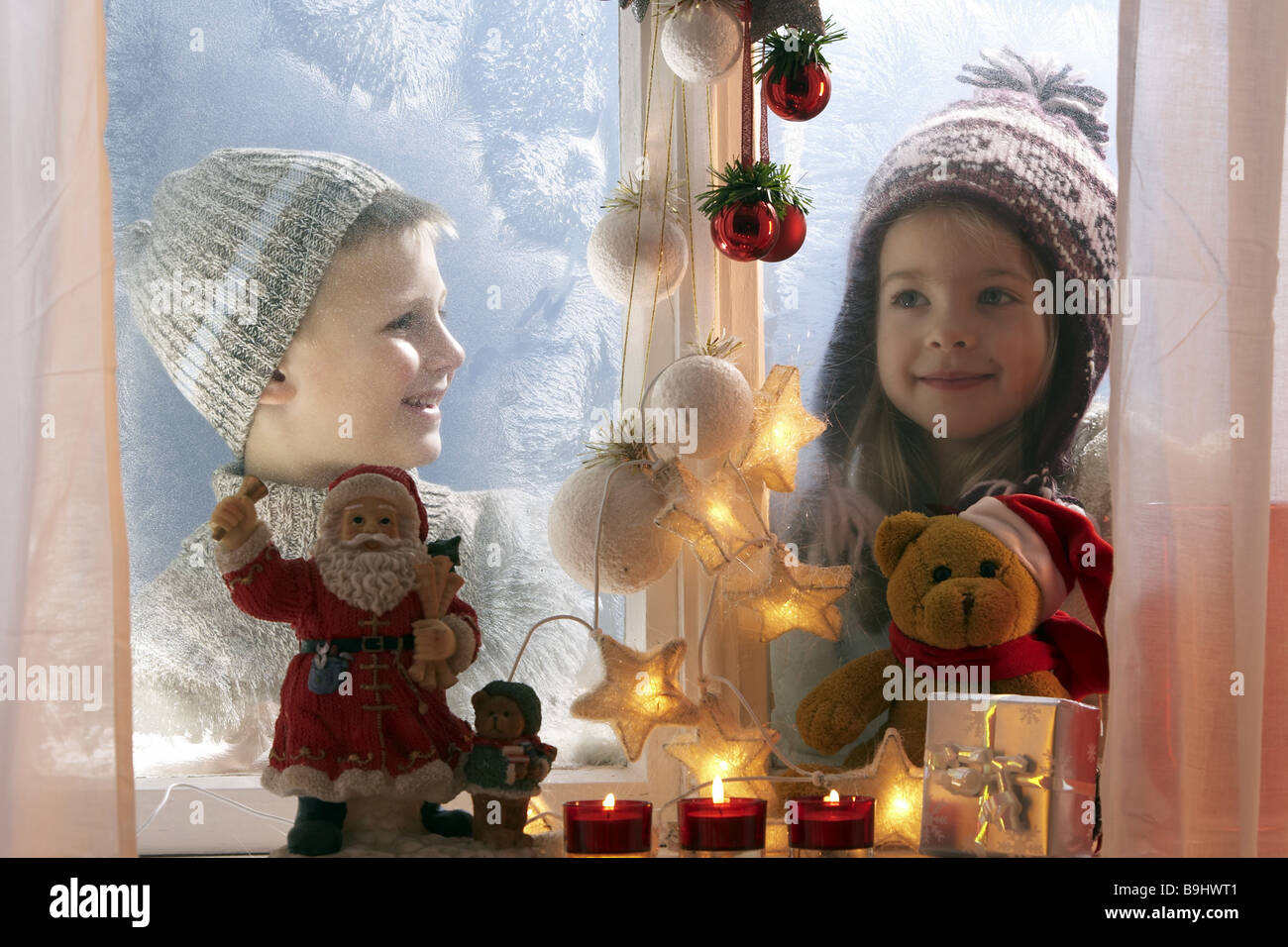 Winter-Geschwister Blick fröhlich Fenster Eisblumen Weihnachtsdekoration Porträt Serie Menschen Kinder Kind-Porträt Knaben Stockfoto
