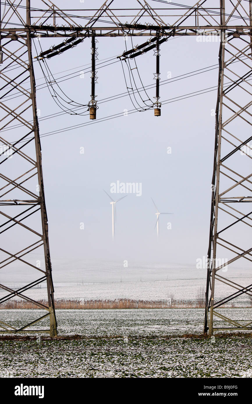 Strommasten und Windkraftanlagen im Nebel Stockfoto