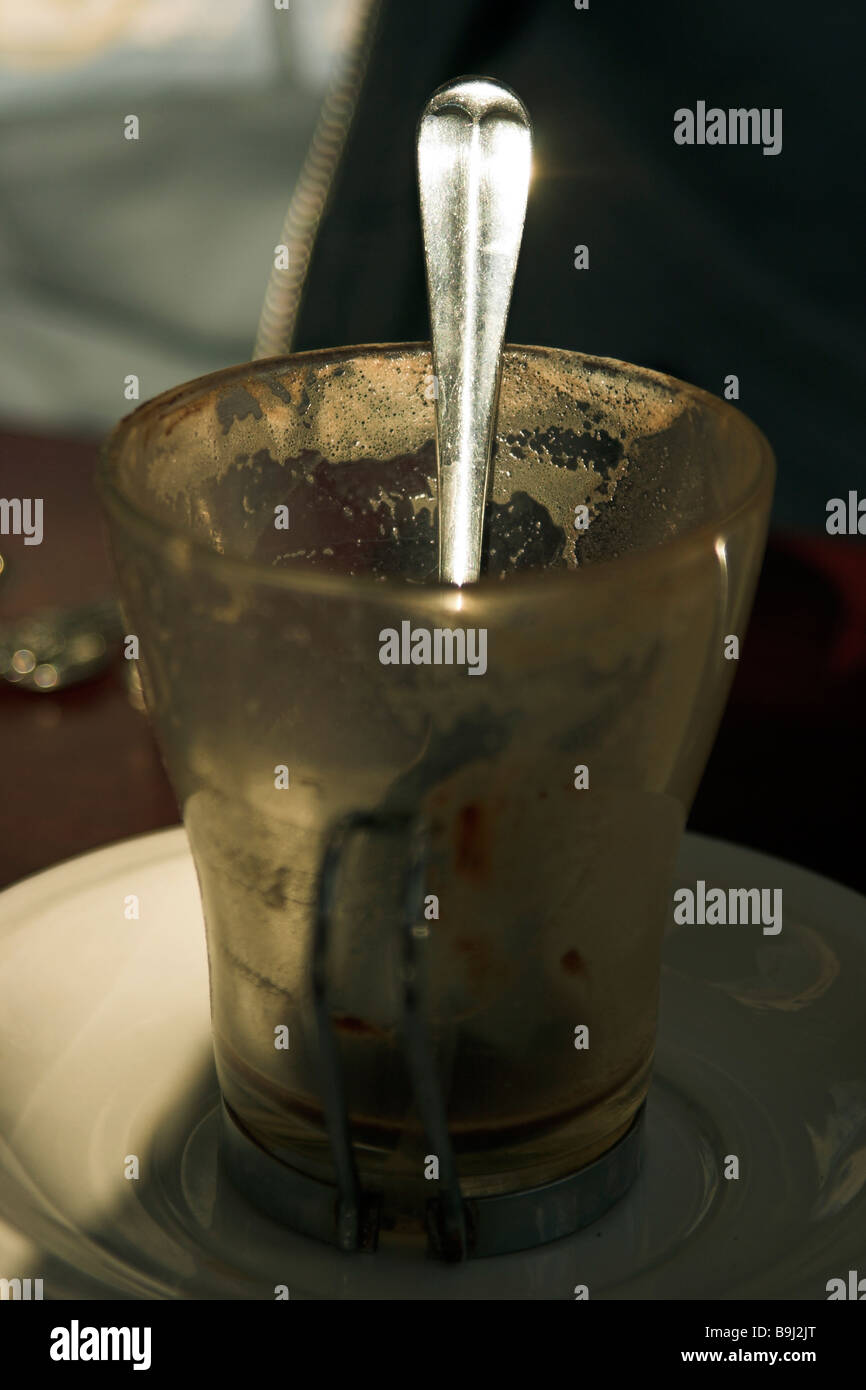 Sonnenlicht glitzerte aus Löffelstiel im leeren Glas Kaffee Tasse Stockfoto