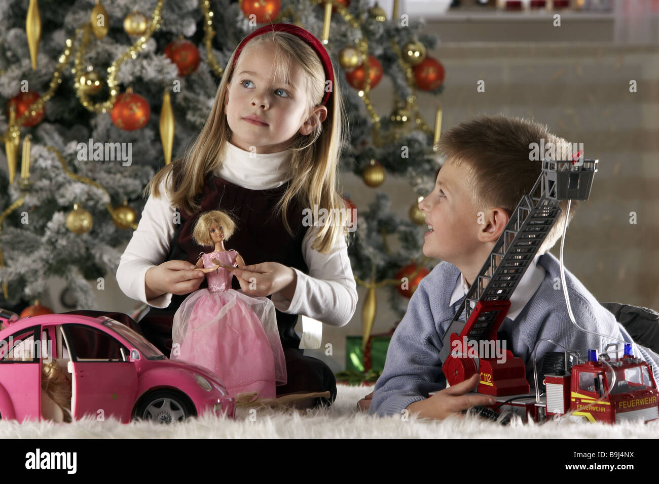 Weihnachtsspielzeug Geschwister spielt semi-Porträt Menschen Kinder 5-7 Jahre zwei Mädchen Junge glücklich lächelnde Kind-Porträt Kindheit Stockfoto