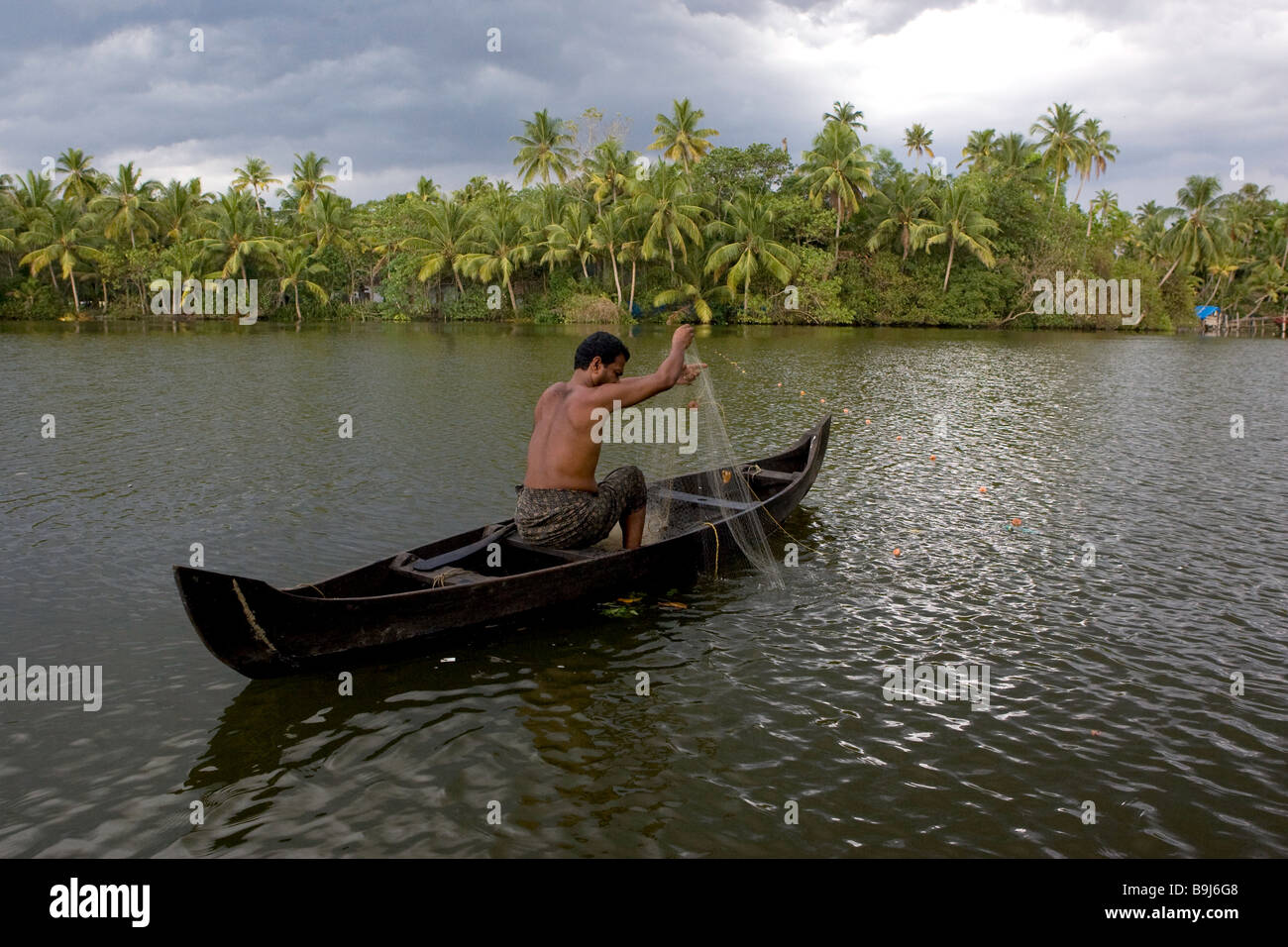 Ein Fischer-Mann wirft seine Netze in den Keralas Backwaters in Kerala, Südindien Stockfoto
