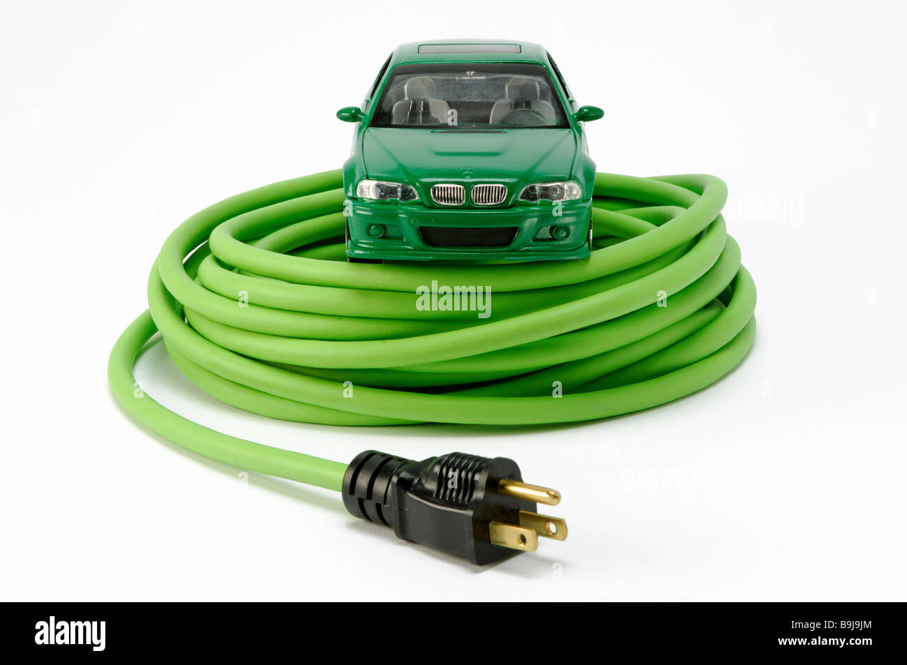 Ein grünes Autos Auto auf einer grünen aufgewickelt elektrischen Strom Verlängerungskabel mit einem Stecker Stockfoto