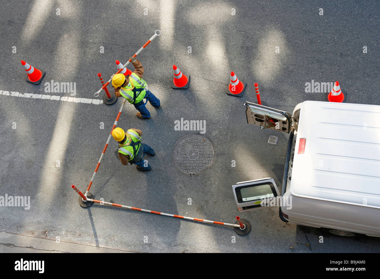 Straße-Dienstprogramm Handwerker, die Barrieren rund um einen Schacht. Stockfoto