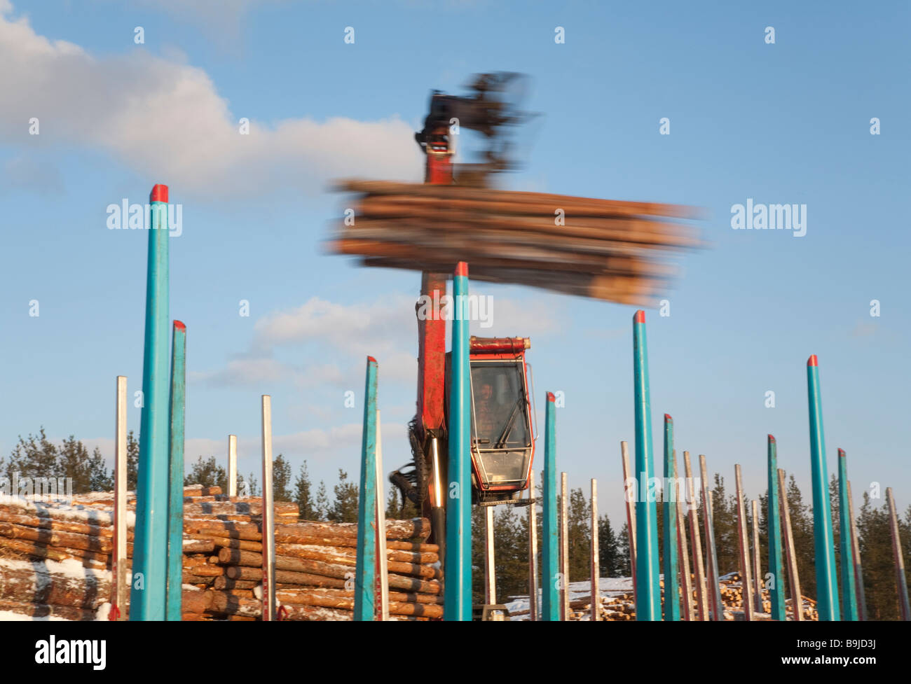 Log LKW-Fahrer mit LKW-Kran und Verladung Protokolle zu Ladung Log Zugwagen auf Eisenbahndepot im Winter. Finnland Stockfoto