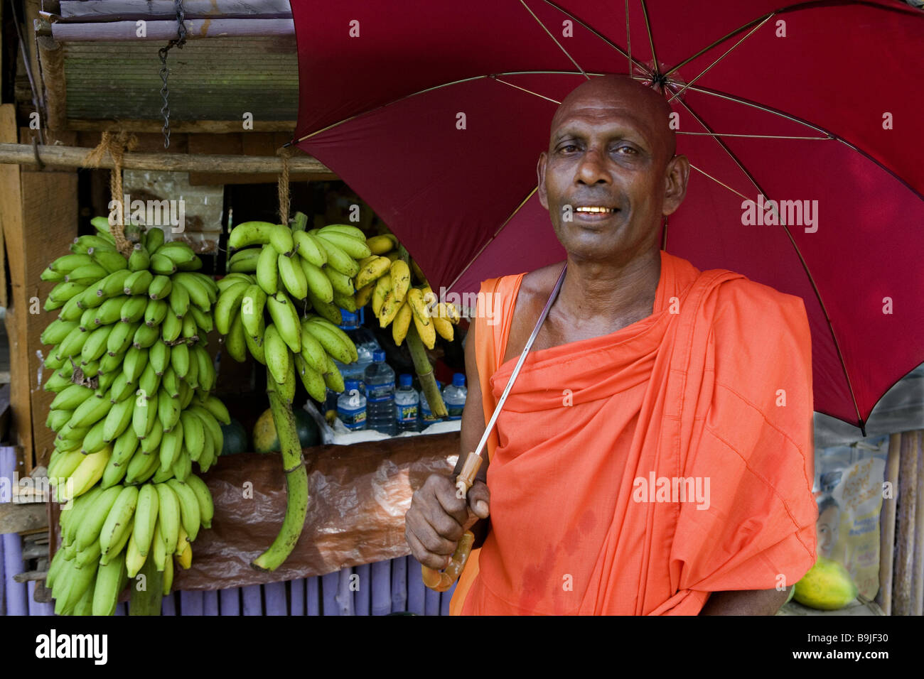Sri Lanka-Marktstand Mönch Regenschirm Asien Südasien Leute Mann Gläubiger Kleid Kutte orange Regenschirm Sonnenschirm außerhalb symbol Stockfoto