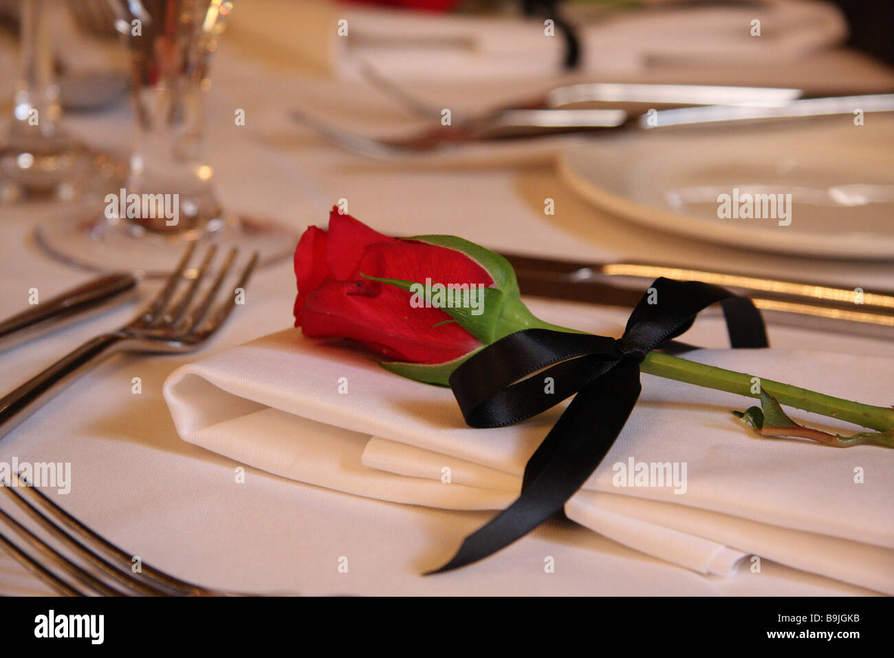 Eine Rose auf einer Serviette gebunden mit schwarzer Seide auf einem Tisch in einer Hochzeit Frühstück Stockfoto