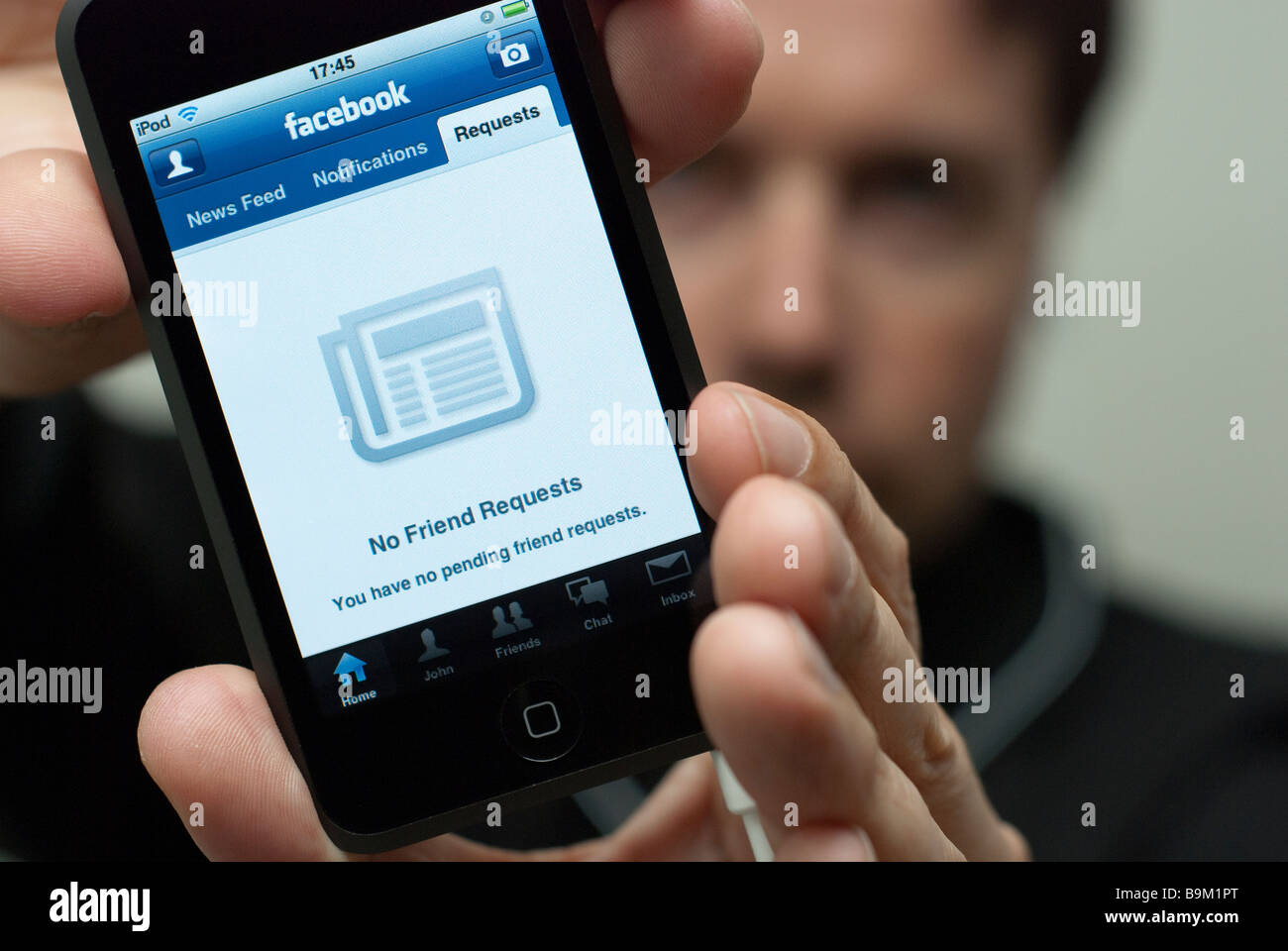 Mann hält einen Apple iPod Touch, die keine Freundschaftsanfragen von Facebook-Social-Networking-Anwendung auf dem Display Stockfoto