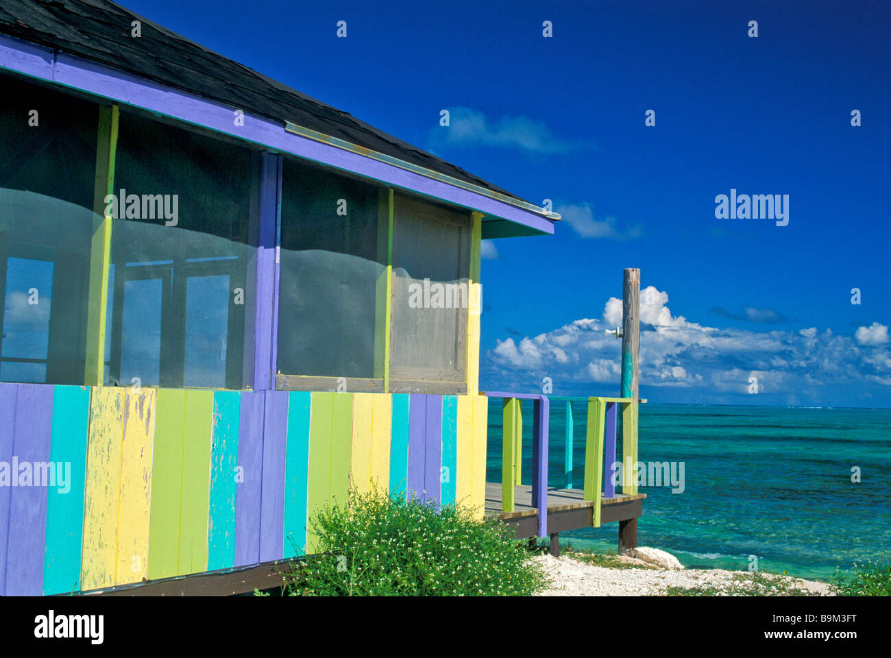 Bunte lila gelb und grün abgeschirmt Gebäude neben klare grüne karibische Wasser Stillleben landschaftlich Stockfoto