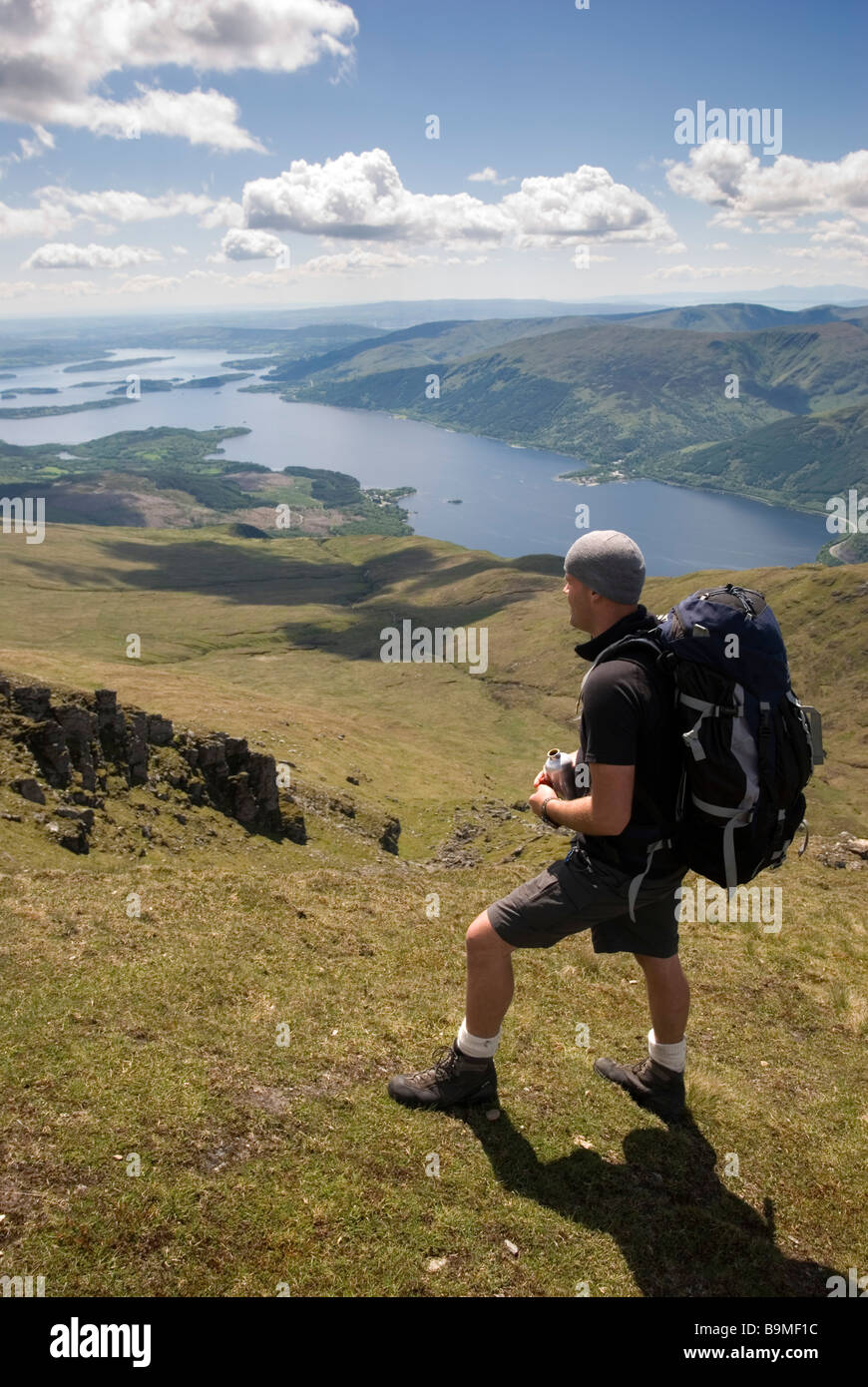 Ein Wanderer schaut auf die atemberaubende Aussicht vom Gipfel des Ben Lomond an einem sonnigen Tag, Stirlingshire, Schottland Stockfoto