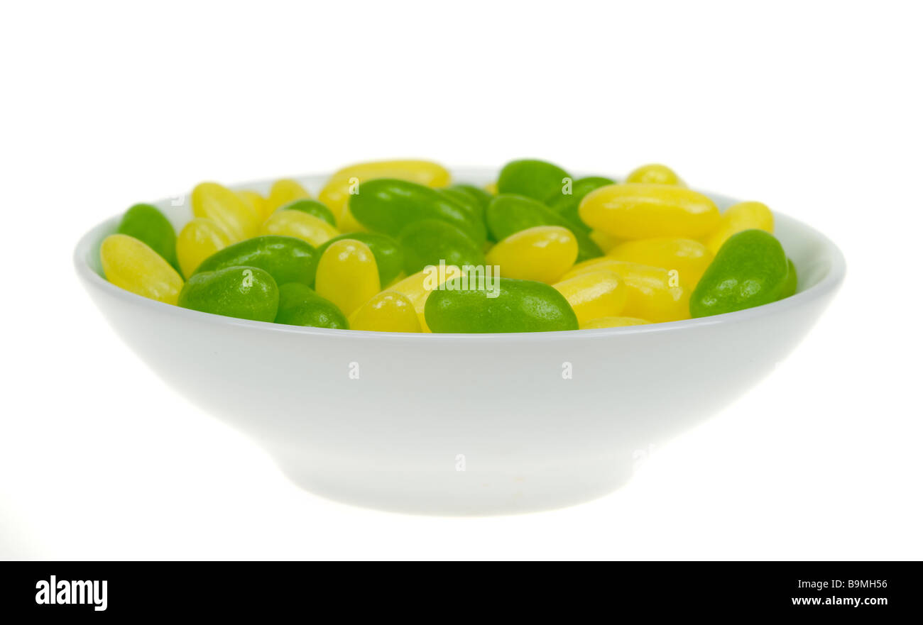 eine Schüssel mit grünen und gelben Gummibärchen isoliert auf weißem Hintergrund Stockfoto