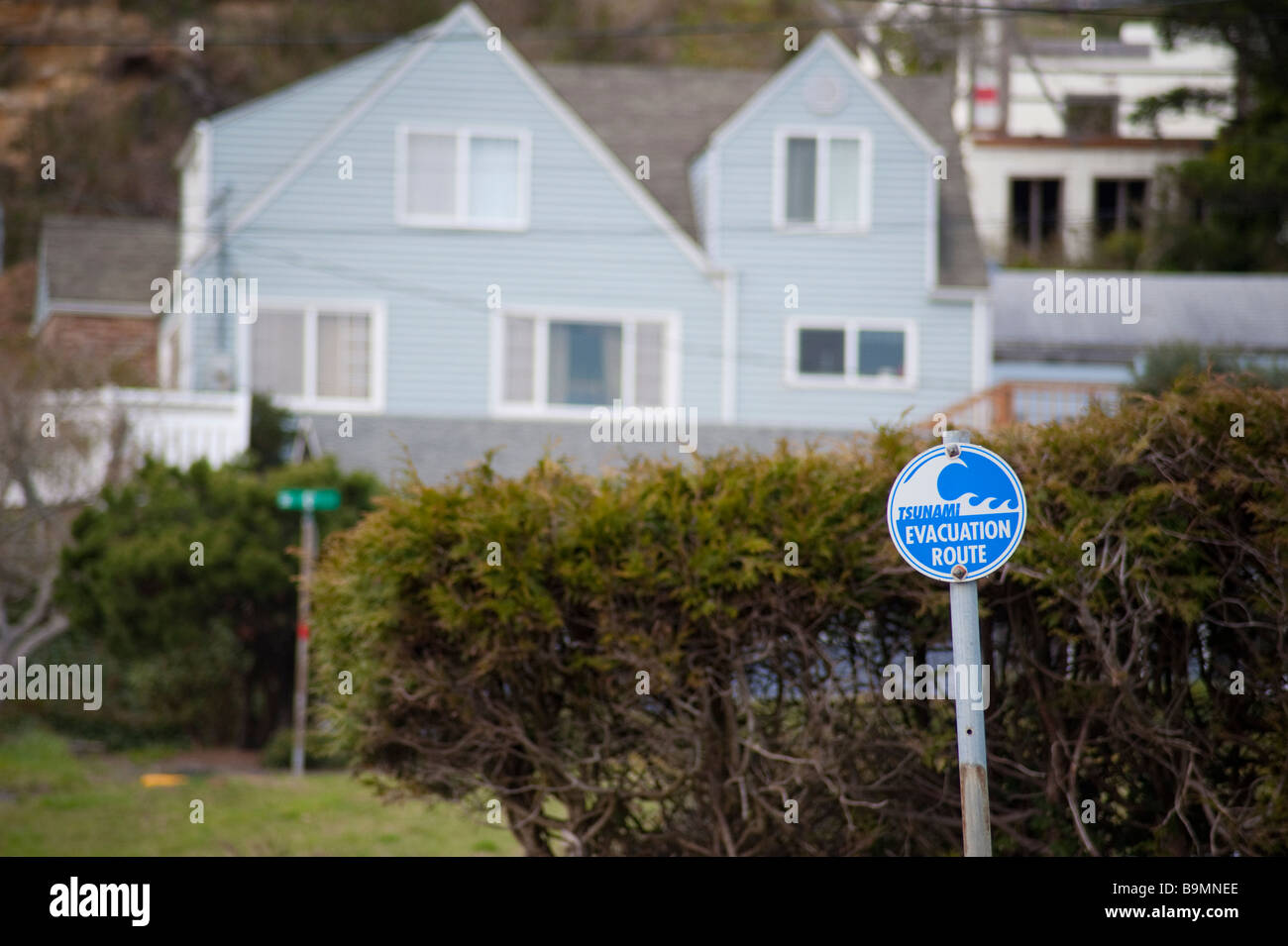 Zeichen markieren einen Rettungsweg für Tsunamis mit Häusern im Hintergrund Stockfoto