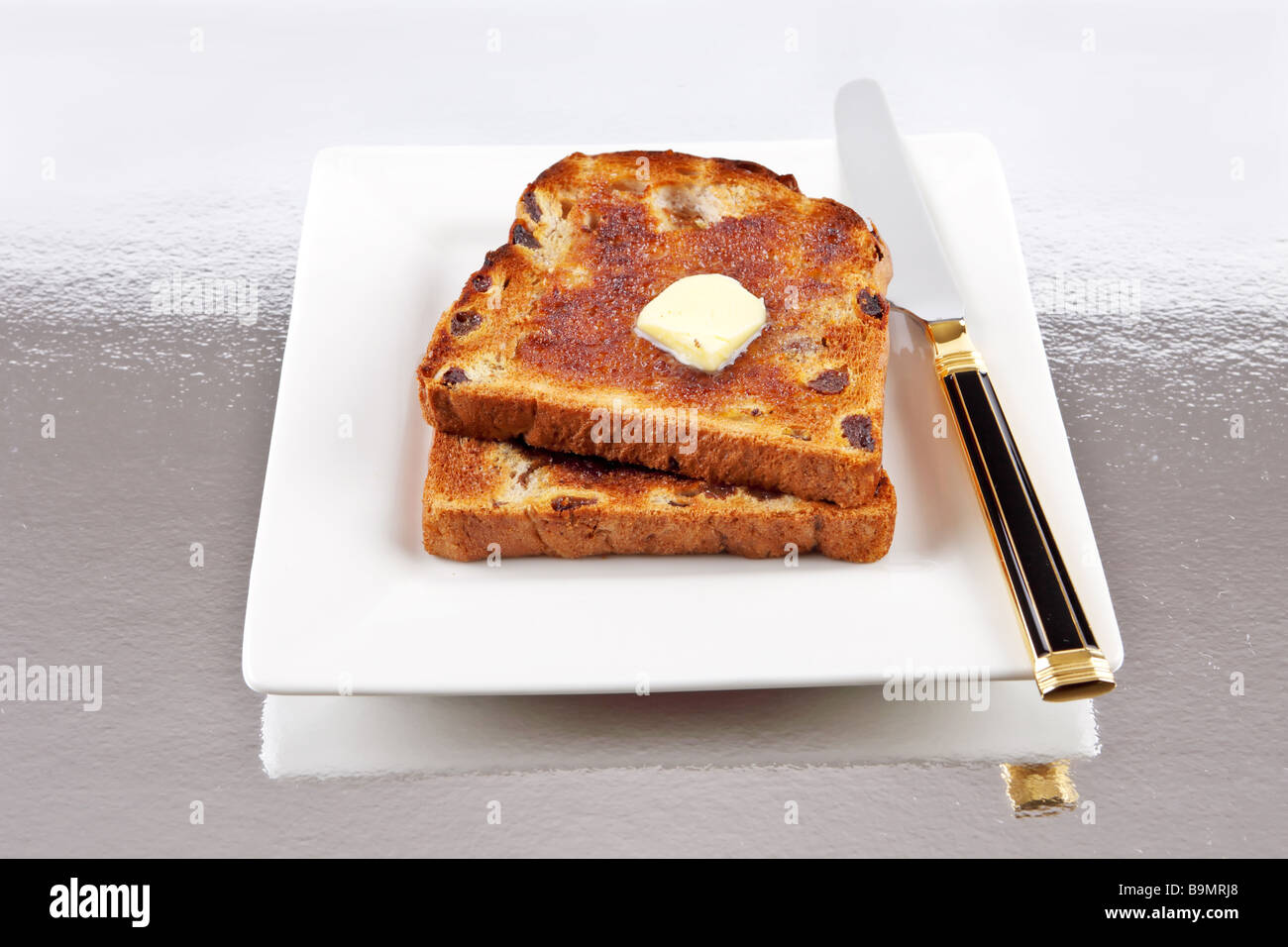 Zwei Scheiben Rosinen Toast mit Butter und Messer auf einem Teller Stockfoto