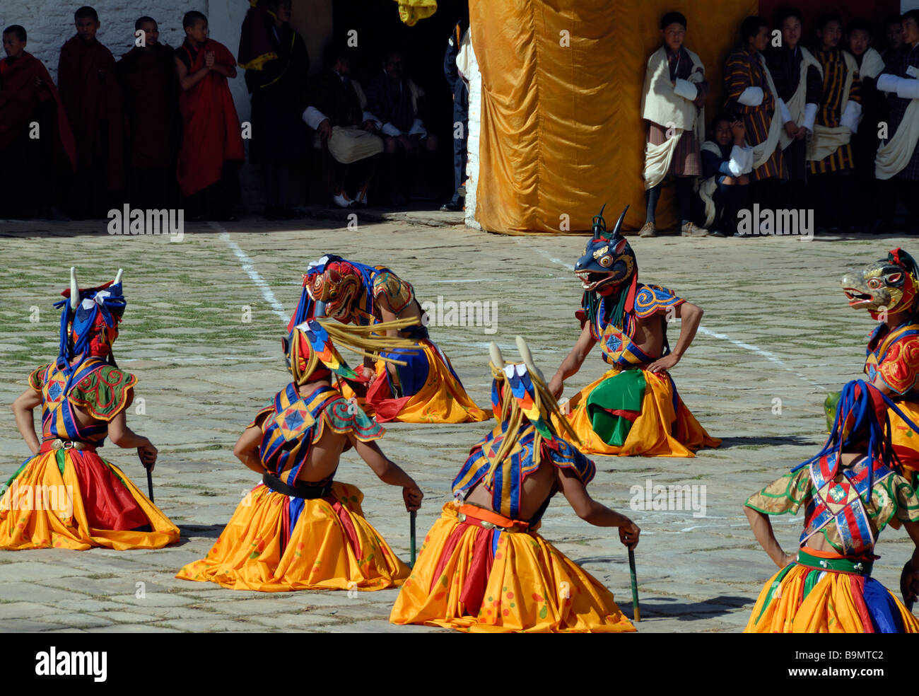 Tänzer im bunten Kleid und bemalten Tiermasken erlassen eine moralische Fabel im Rathaushof Mongar Dzong Bhutans Stockfoto