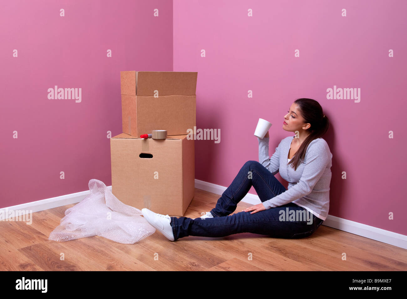 Eine attraktive junge Frau nimmt sich eine Auszeit in ihrem Haus-Umzug Stockfoto