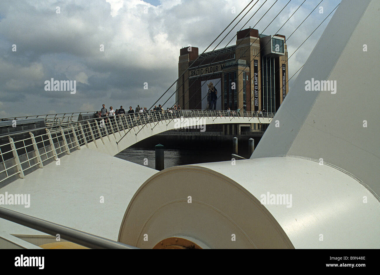 Gateshead, Baltic Arts Centre, gesehen durch die Millennium Bridge, mit dem Gang der Brücke im Vordergrund, an einem stürmischen Tag drehen. Stockfoto