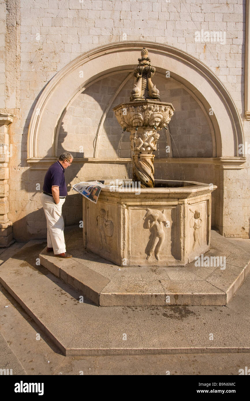Lokale Mann liest Zeitung durch kleine Onofrio s Brunnen in der ummauerten Stadt von Dubrovnik im Sommersonnenschein dalmatinischen Küste Kroatien Stockfoto