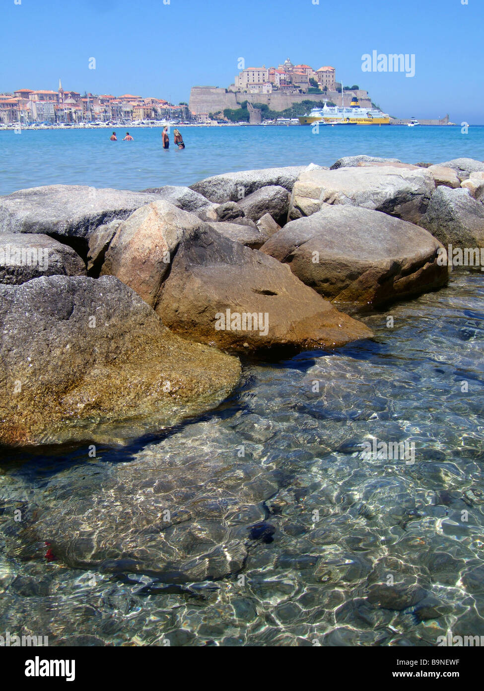 Das Meer, Meer und Felsen mit der Zitadelle von Calvi im Hintergrund Calvi, Korsika, Frankreich. Stockfoto