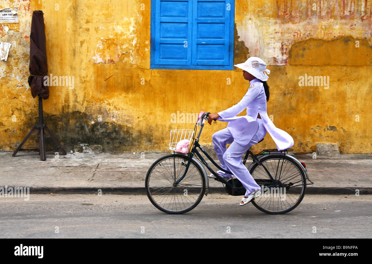 Straßenszene. Young Woman Mädchen mit den traditionellen Seidenkleid Fahrradtouren ein Push in Hoi an, Vietnam Stockfoto