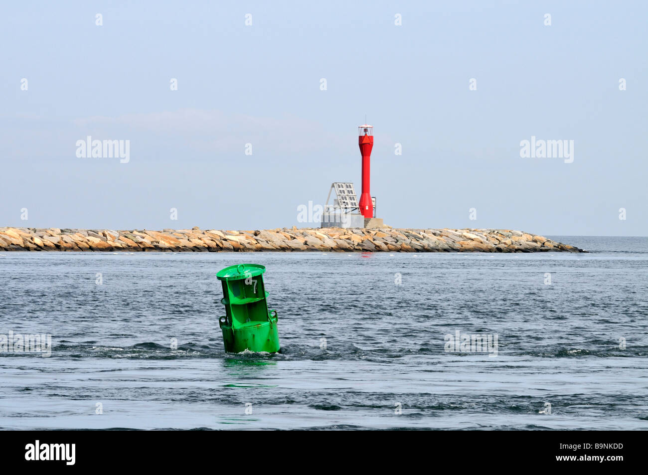 Navigations-Kanal Marker im Ozean mit einem grünen können und eine rote solar powered Daymarker auf steinernen Steg. Stockfoto