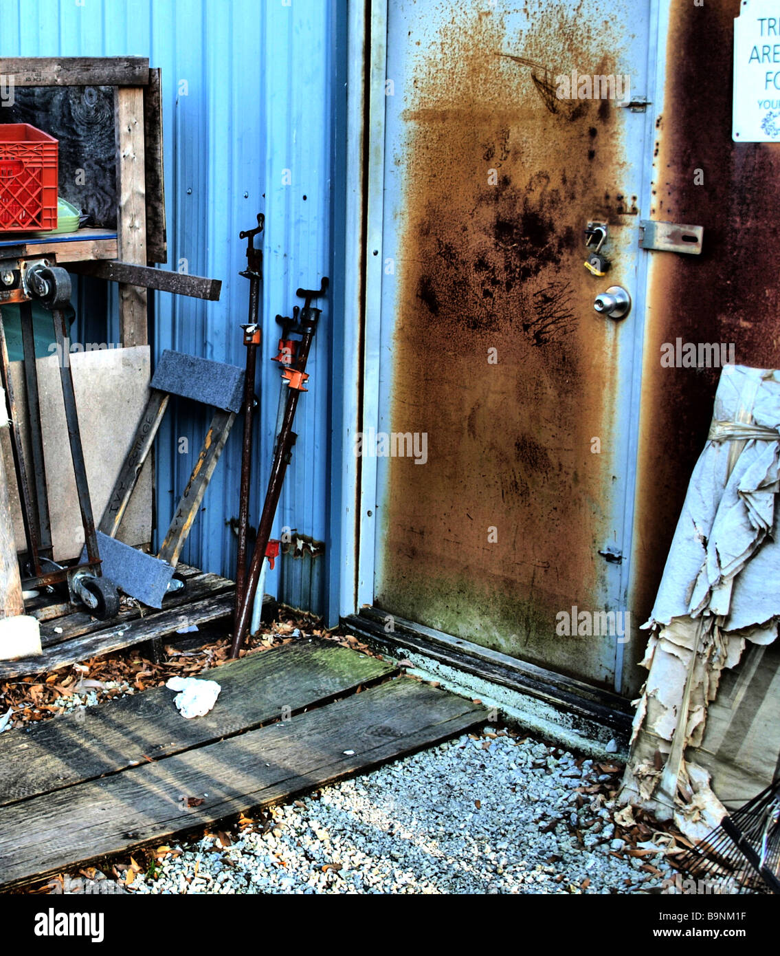 blaue Tür und teilweise Gebäude mit Werkzeuge-Boxen und Beplankung, verrostet Stockfoto