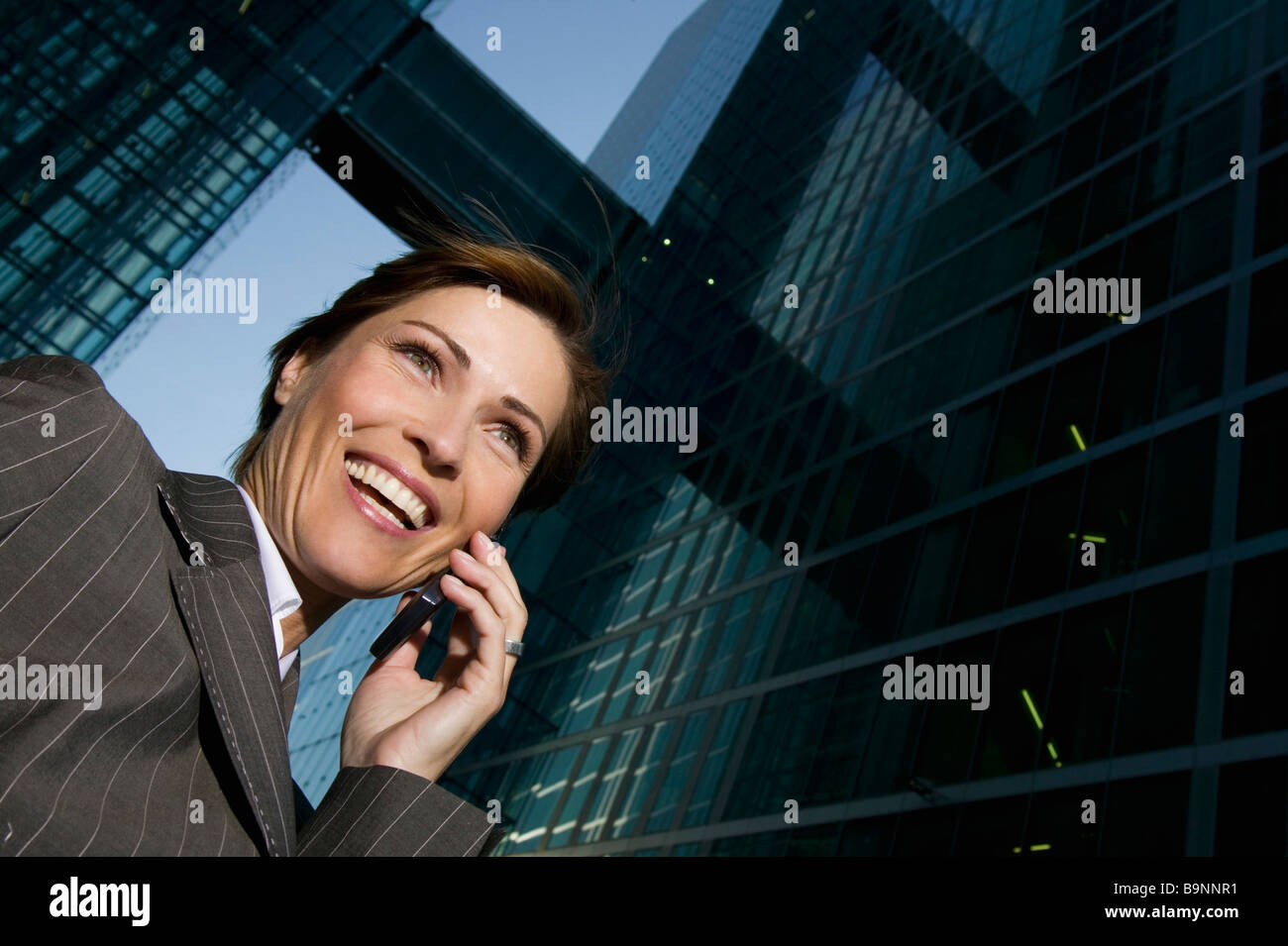 niedrigen Winkel Porträt von Reife Geschäftsfrau telefonieren mit Handy vor Bürogebäude Stockfoto