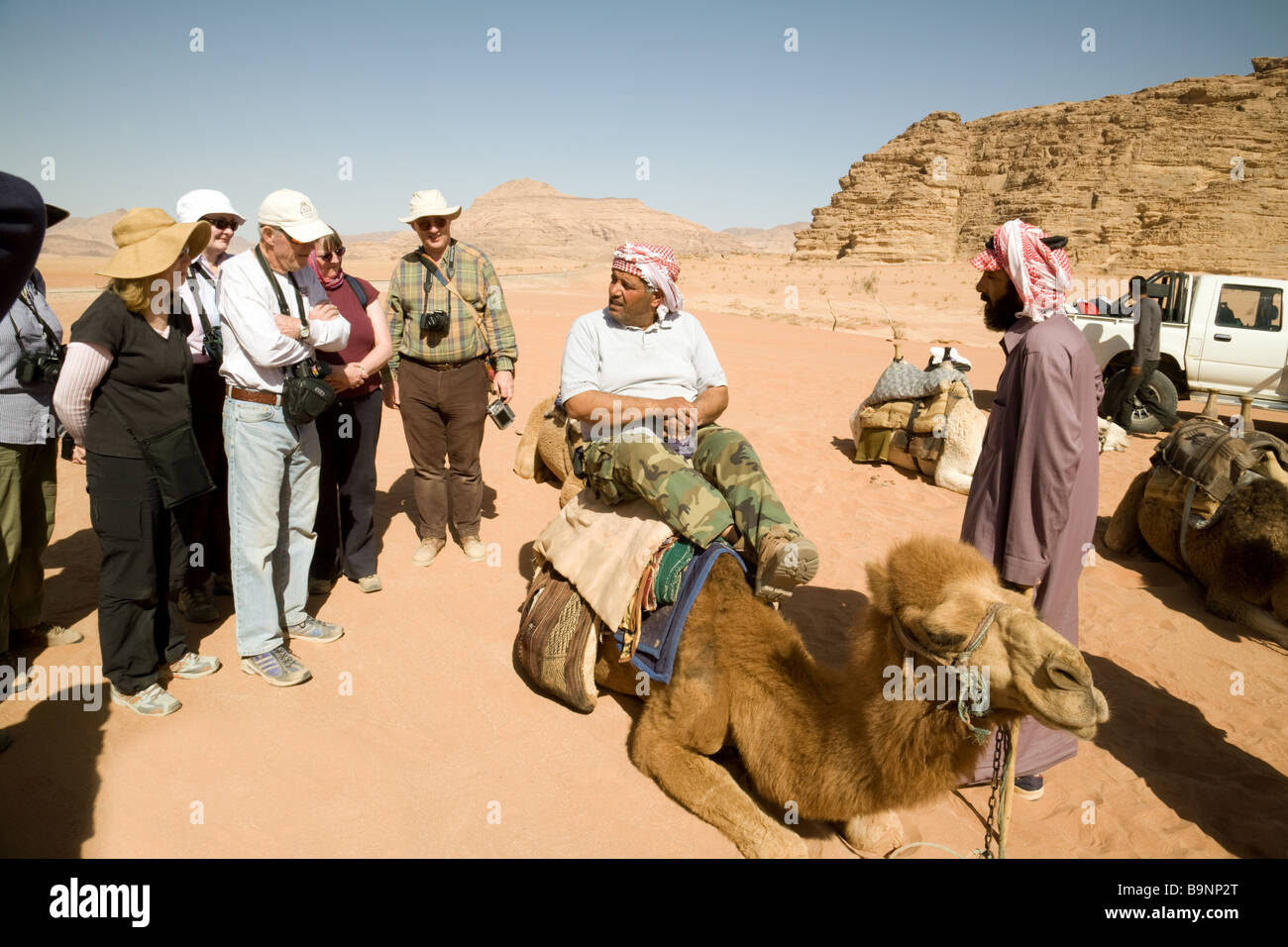 Ein Beduine arabischen lehrt im mittleren Alter westliche Touristen, wie Sie einen Kamelritt; Wadi Rum, Jordanien Stockfoto