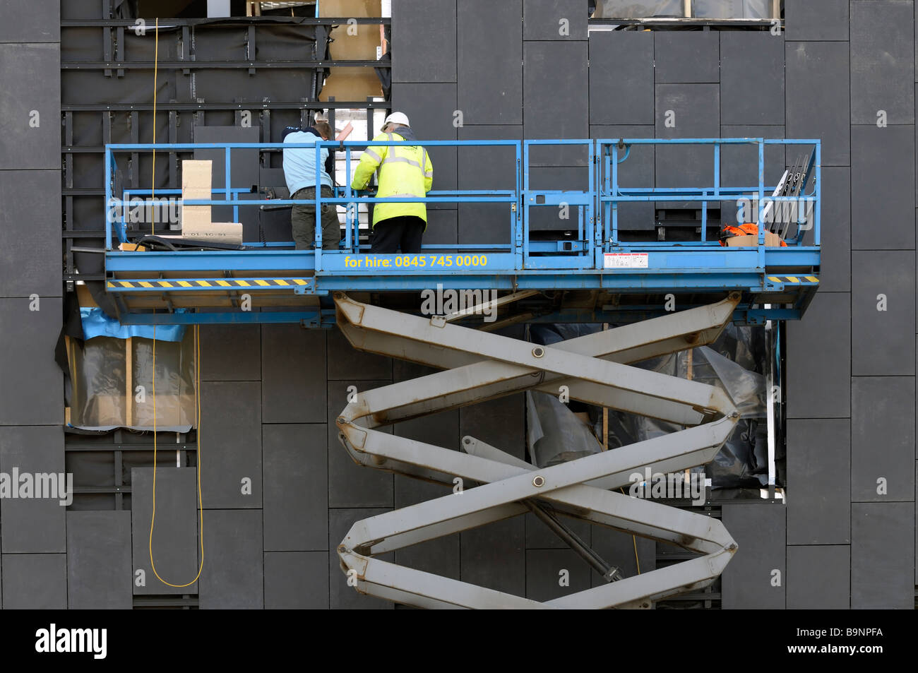 Arbeiter mit einem Scherenhubtisch Verkleidung in ein neues Gebäude an der Lancaster University passen Stockfoto