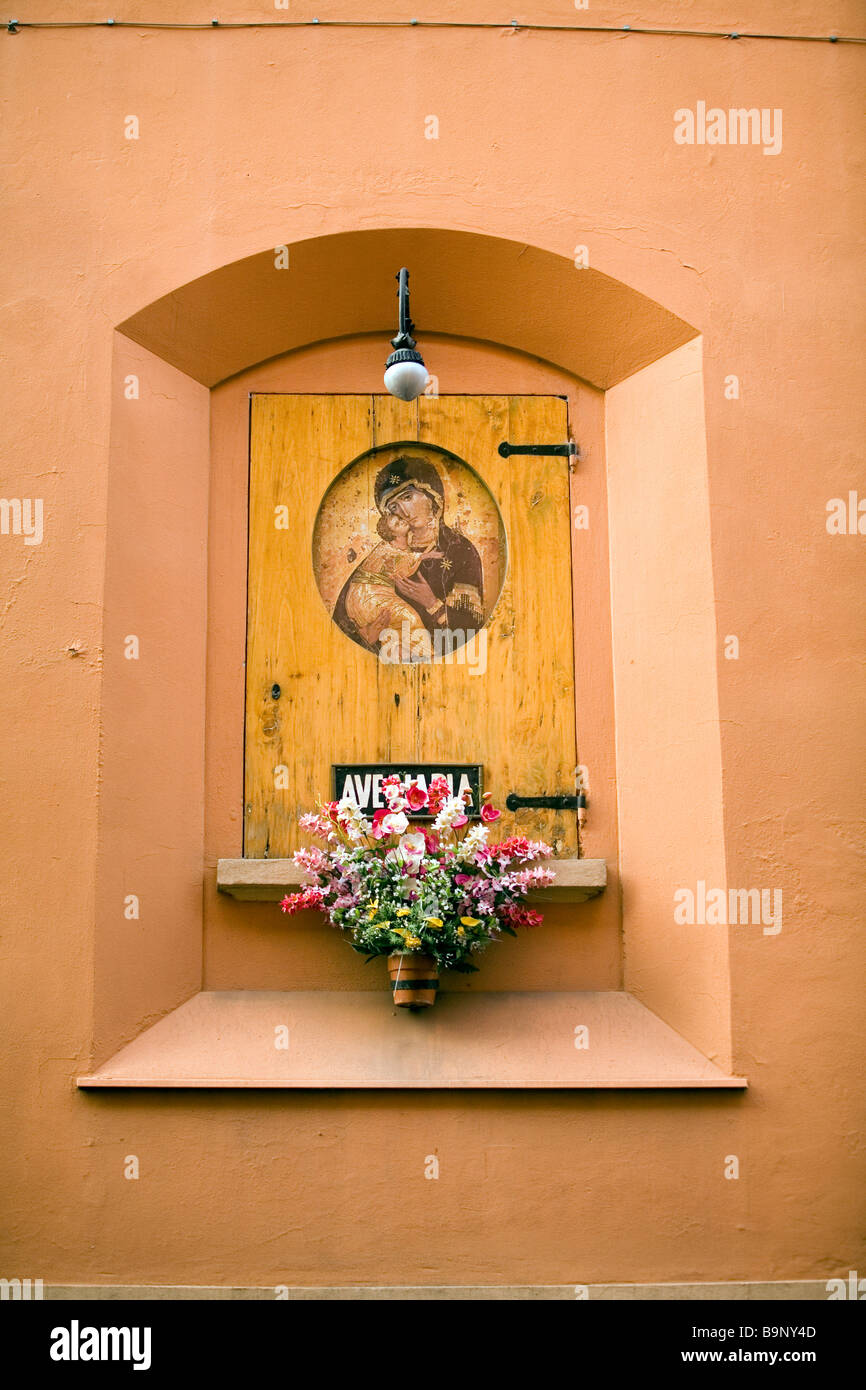 Eine religiöse Ikonographie und frische Blumen auf einer Wand in Bologna Ital Stockfoto
