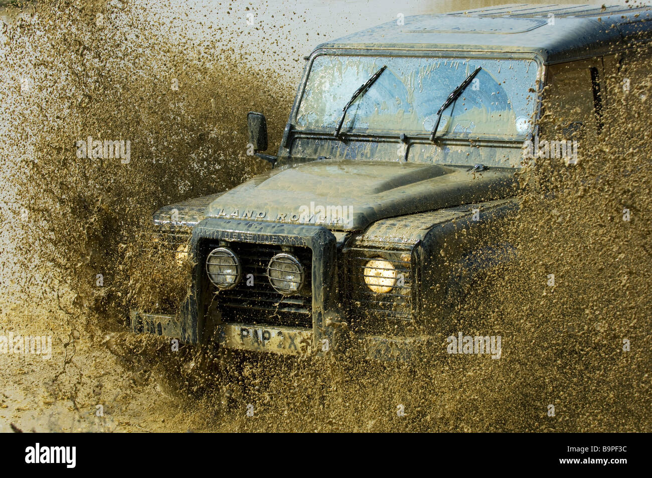 Ein Land Rover Defender 90 beschleunigt durch eine überschwemmte Straße in Slindon West Sussex UK während einer Off Road-Übung Stockfoto