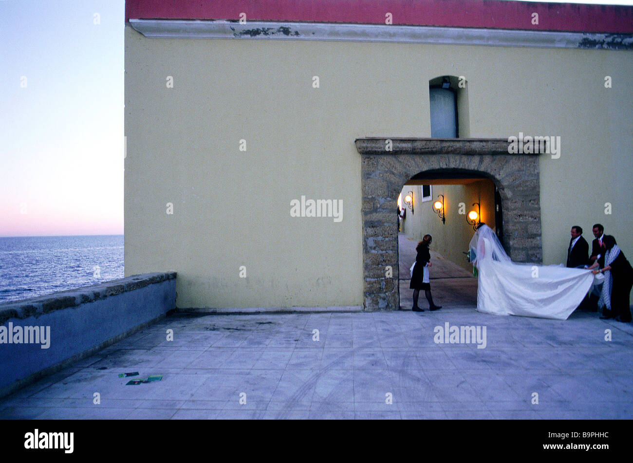 Spanien, Andalusien, Cadiz, Braut mit langen Brautkleid betreten eine Villa für den Empfang Stockfoto