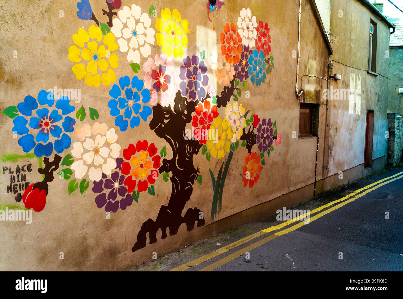 Ein Baum auf der Seite der Wand nach unten eine Gasse in Kilkee Co Clare gemalt Stockfoto