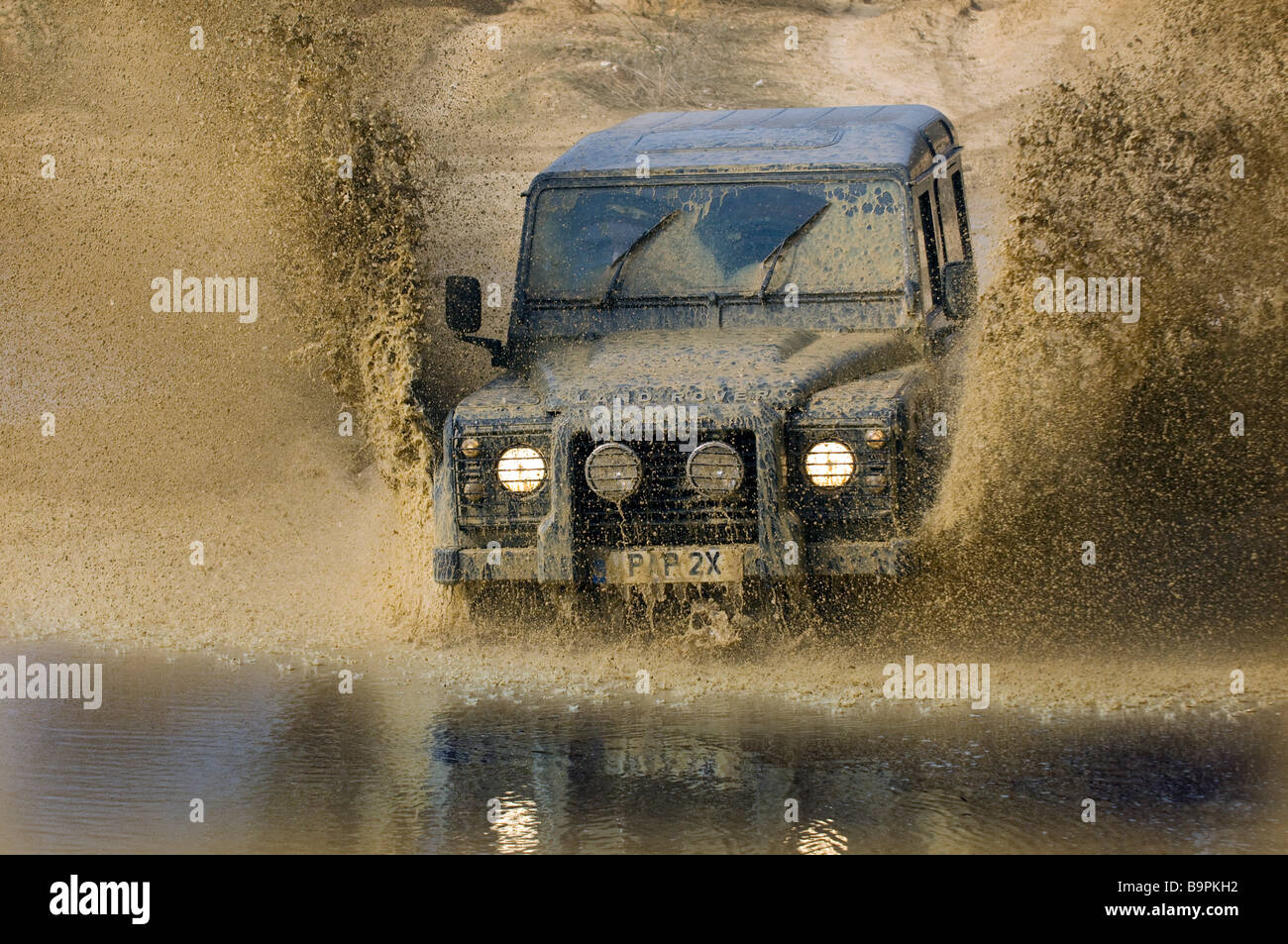 Ein Land Rover Defender 90 beschleunigt durch eine überschwemmte Straße in Slindon West Sussex UK während einer Off Road-Übung Stockfoto