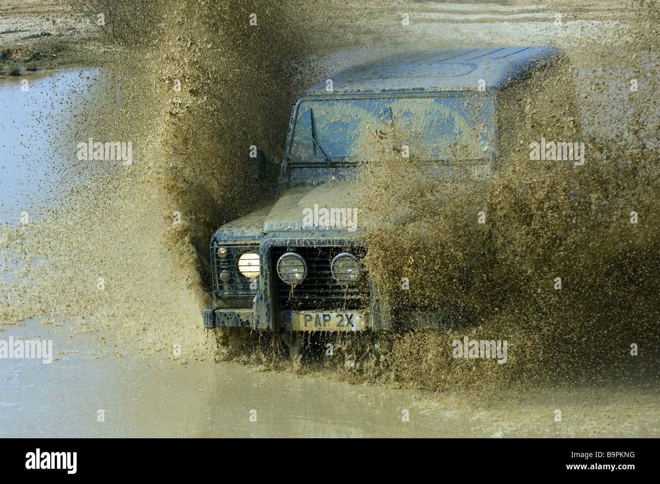 Ein Land Rover Defender 90 beschleunigt durch eine überschwemmte Straße in Slindon West Sussex UK während einer Off Road-Übung Stockfoto