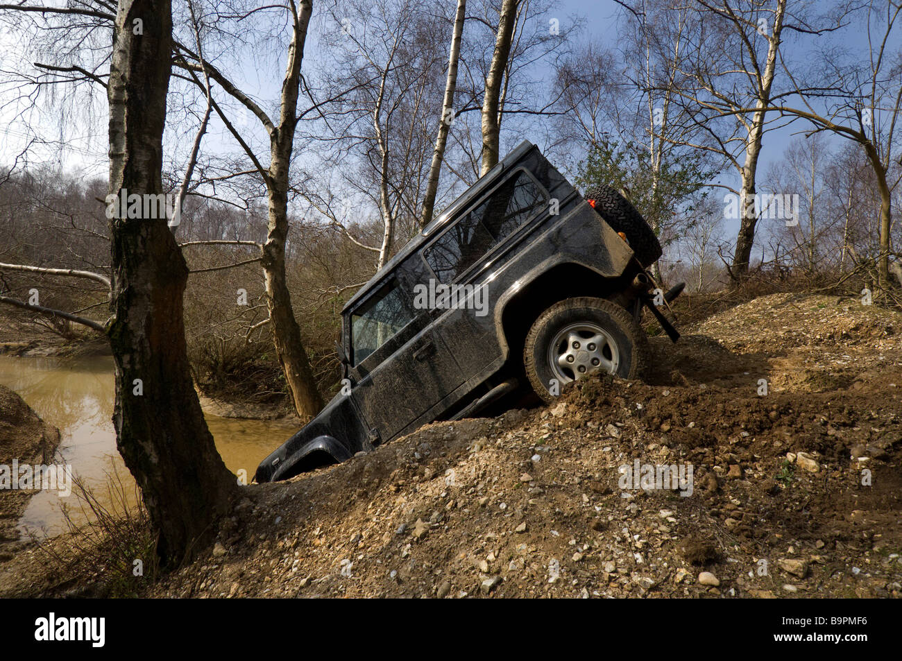 Ein Land Rover Defender 90 schleicht sich eine steile Böschung hinunter. Stockfoto