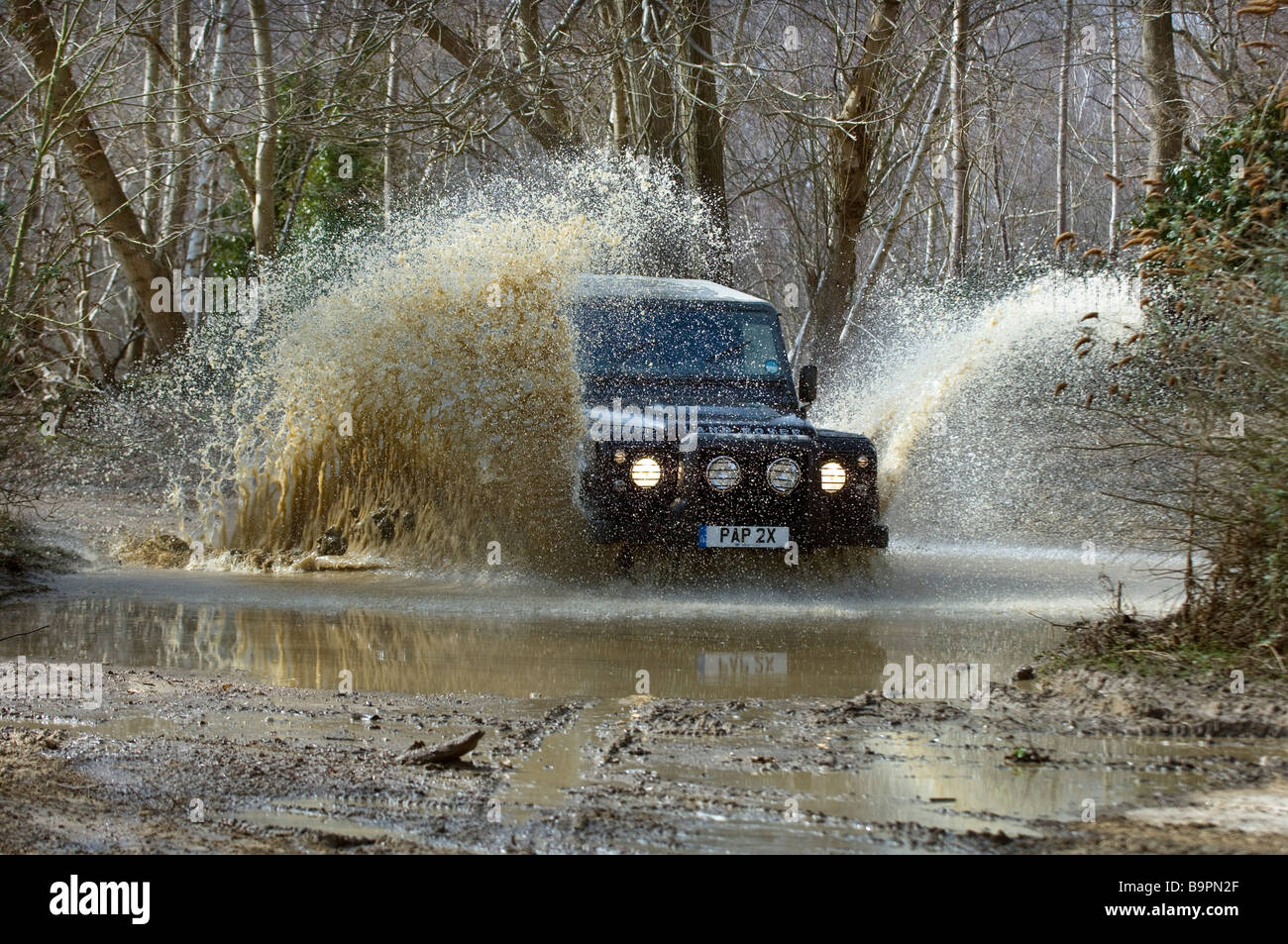 Ein Land Rover Defender 90 Spritzer überflutet Durchgangsgleis in Sussex. Stockfoto