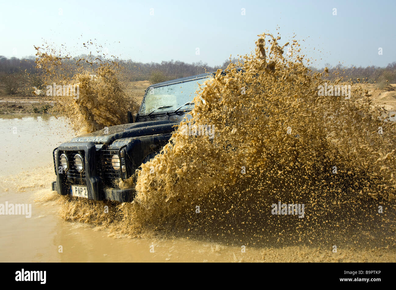 Ein Land Rover Defender 90 beschleunigt durch eine überschwemmte Straße in Slindon West Sussex UK während einer Off Road-Übung Stockfoto