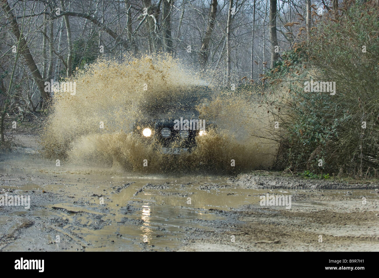 Ein Land Rover Defender 90 Spritzer überflutet Durchgangsgleis im Wald in Slindon West Sussex UK während einer Off Road-Übung. Stockfoto