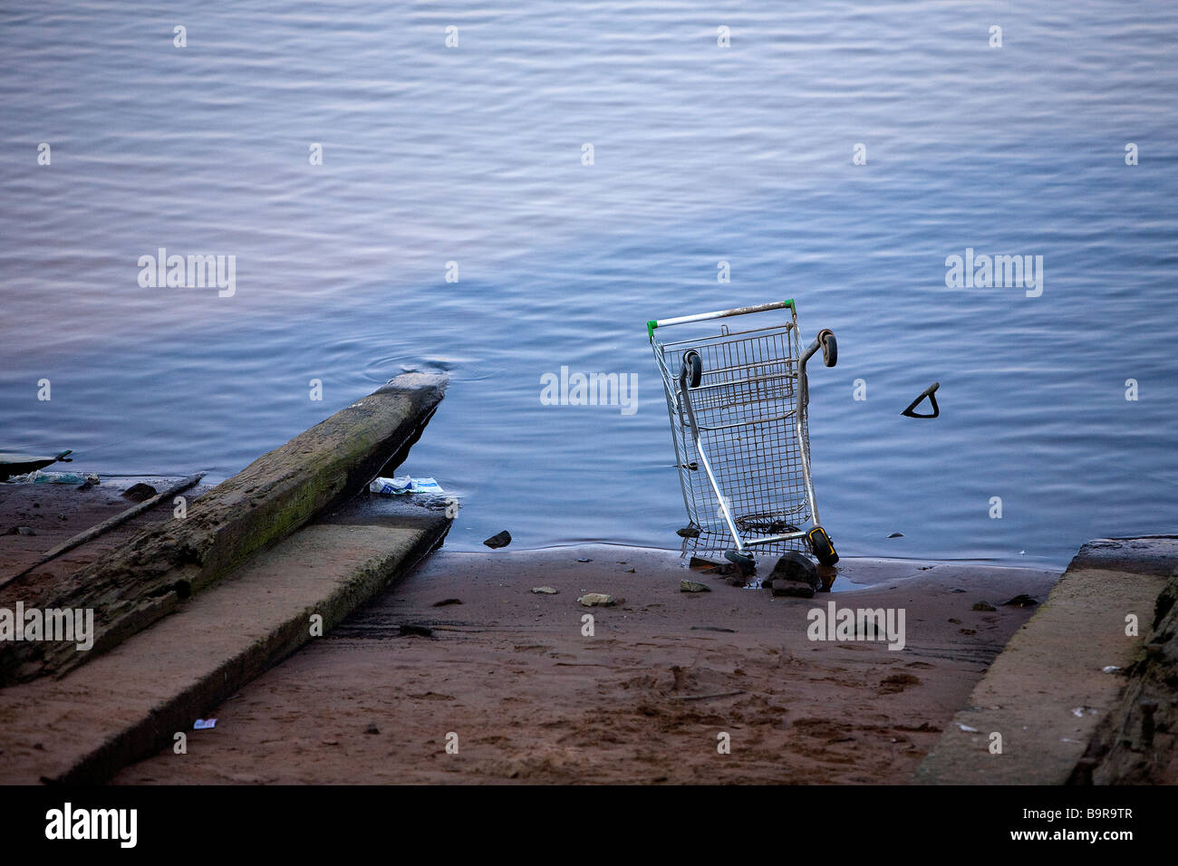 Einen ausrangierten Einkaufswagen liegt bis endete am unteren Rand einen Slip-Weg am Rande des Flusses Mersey Stockfoto