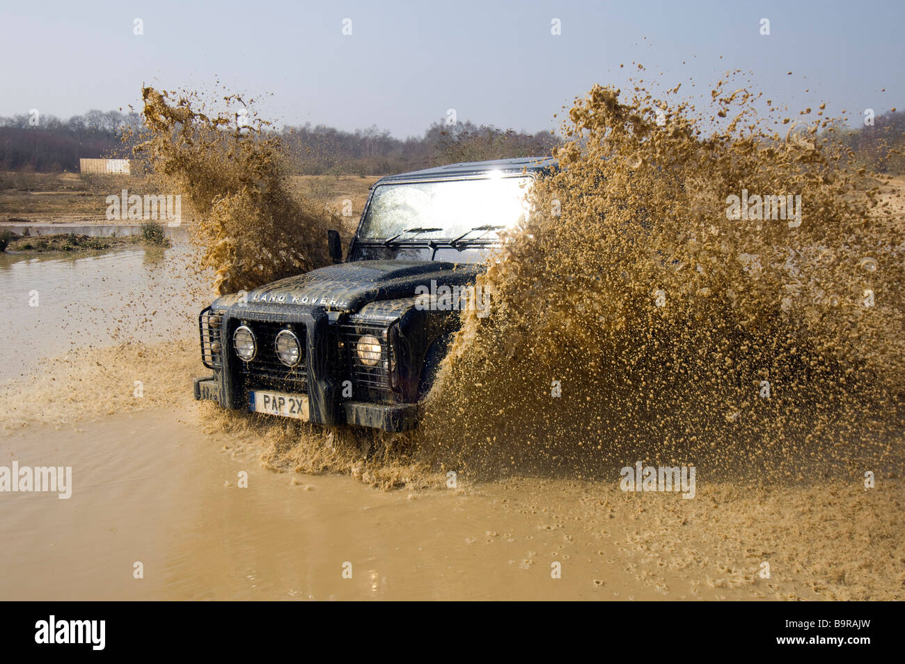 Ein Land Rover Defender 90 beschleunigt durch eine überschwemmte Straße in Slindon West Sussex UK während einer Off Road-Übung Stockfoto