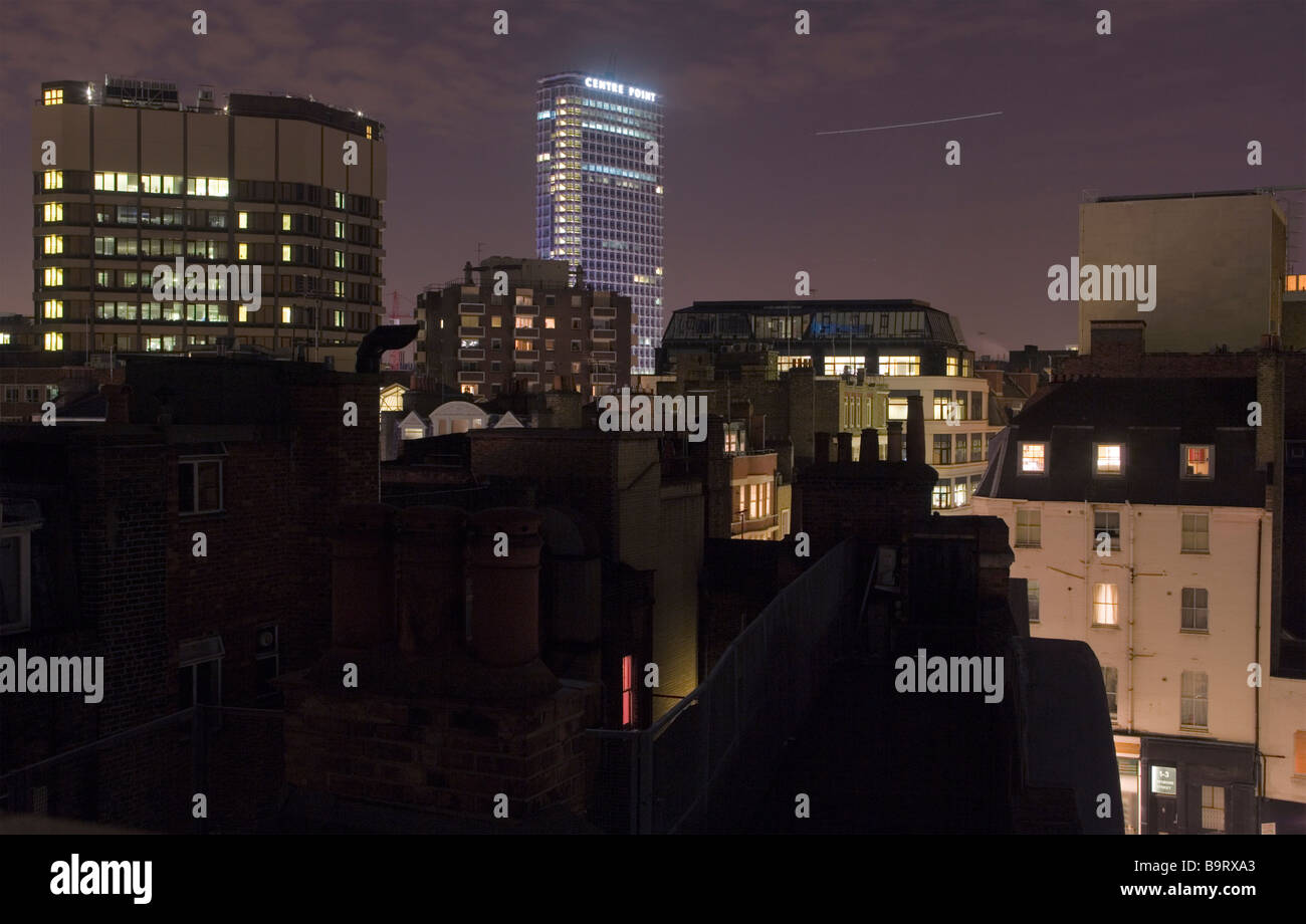 Londons Westend in der Nacht, mit Zentrierspitze Hochhaus in der Ferne und ein Flugzeug über den Himmel Stockfoto
