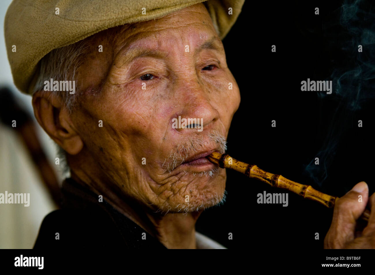Ein chinesischer Mann raucht seine traditionelle Pfeife. Stockfoto