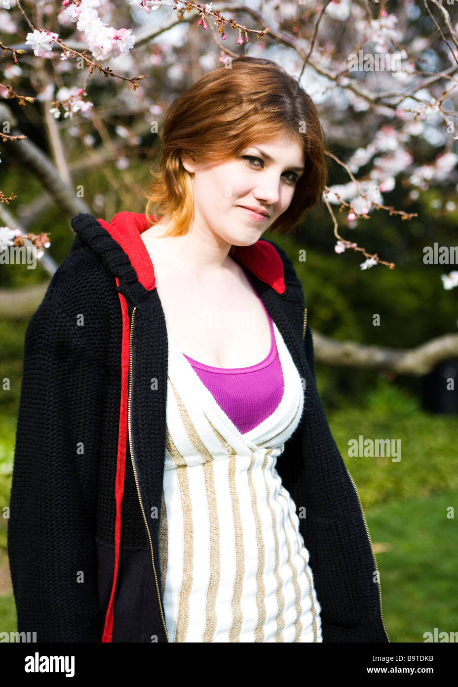 Kaukasische junge weibliche neben Kirschbaum in voller Blüte steht Stockfoto