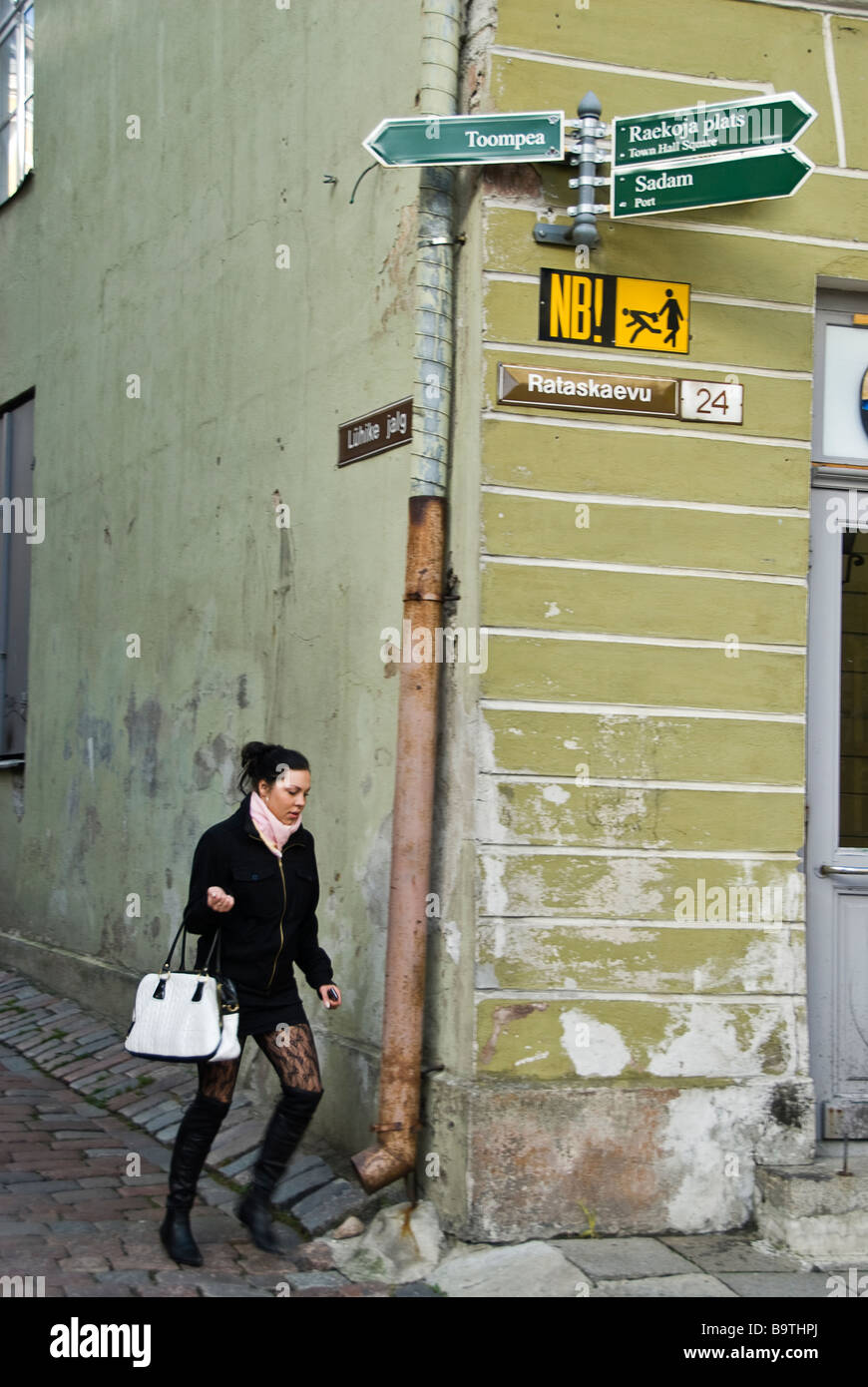 Junge Frau mit Handtasche zu Fuß auf den Straßen von Tallin unter ein Warnsignal für Touristen, Estland, Europa. Stockfoto