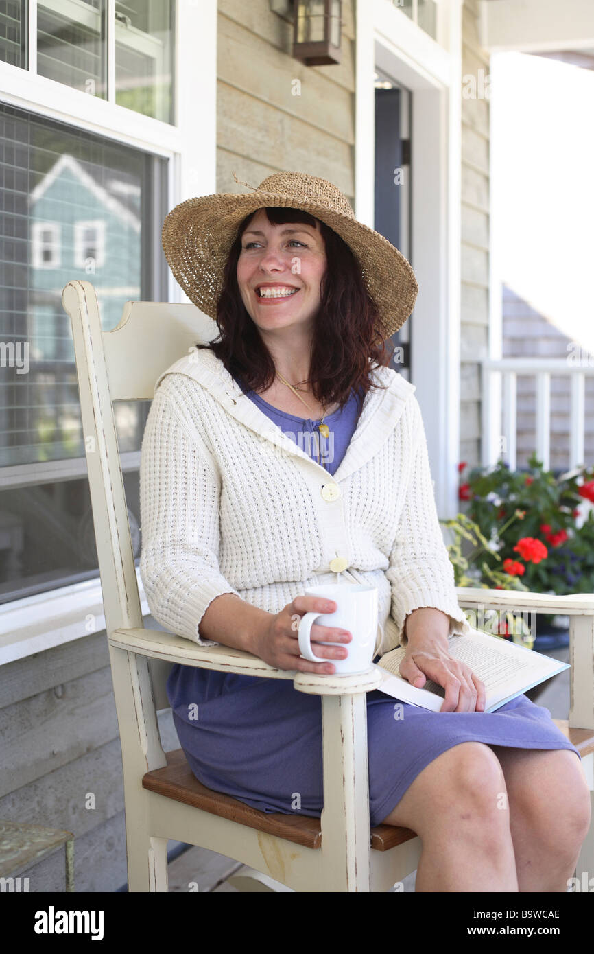 Frau sitzt im Stuhl auf Veranda Stockfoto