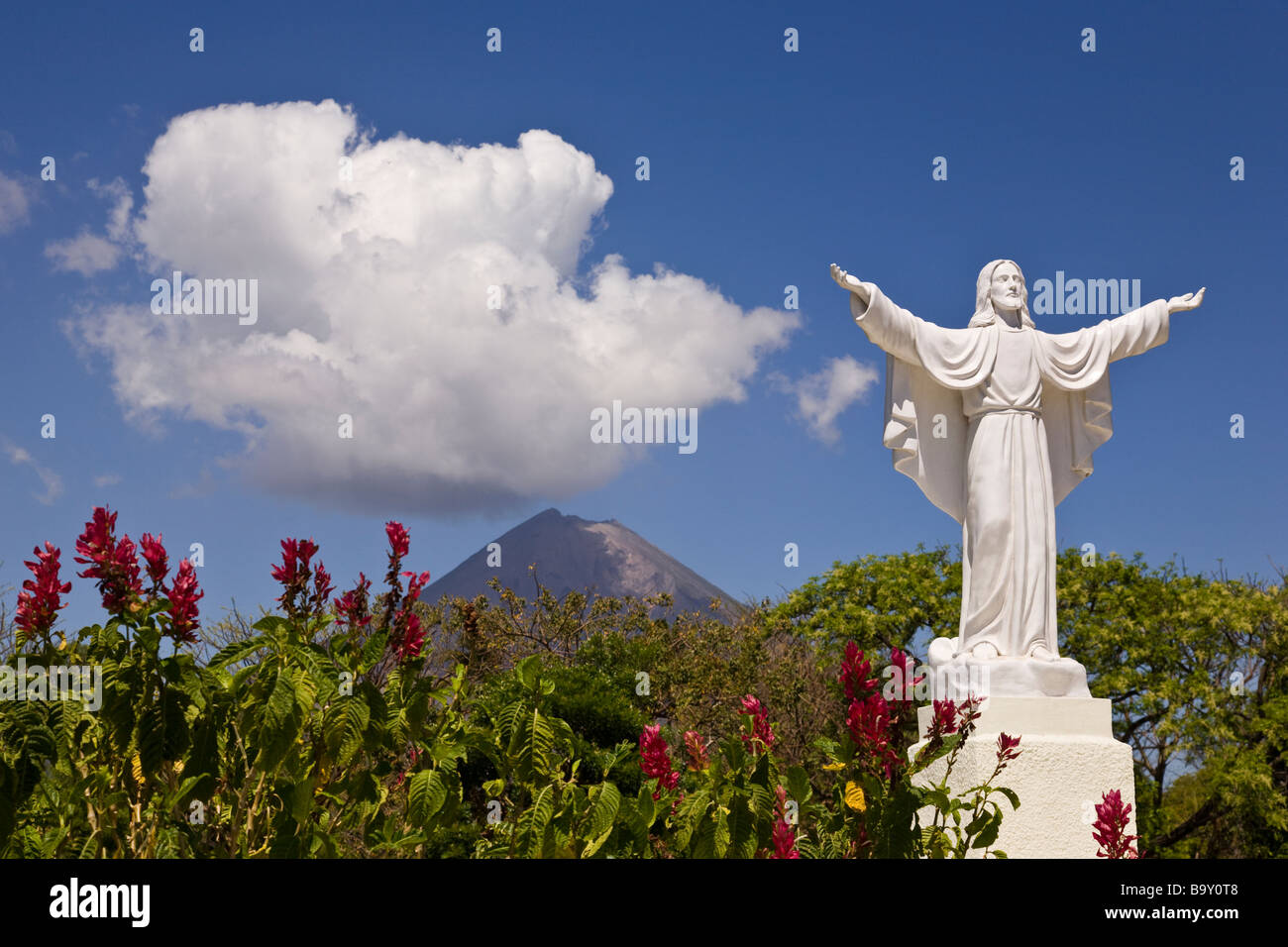 Statue von Jesus an der Cementerio Los Angeles in Moyogalpa, Nicaragua auf der Insel Ometepe mit der Volcan Concepcion hinter droht. Stockfoto