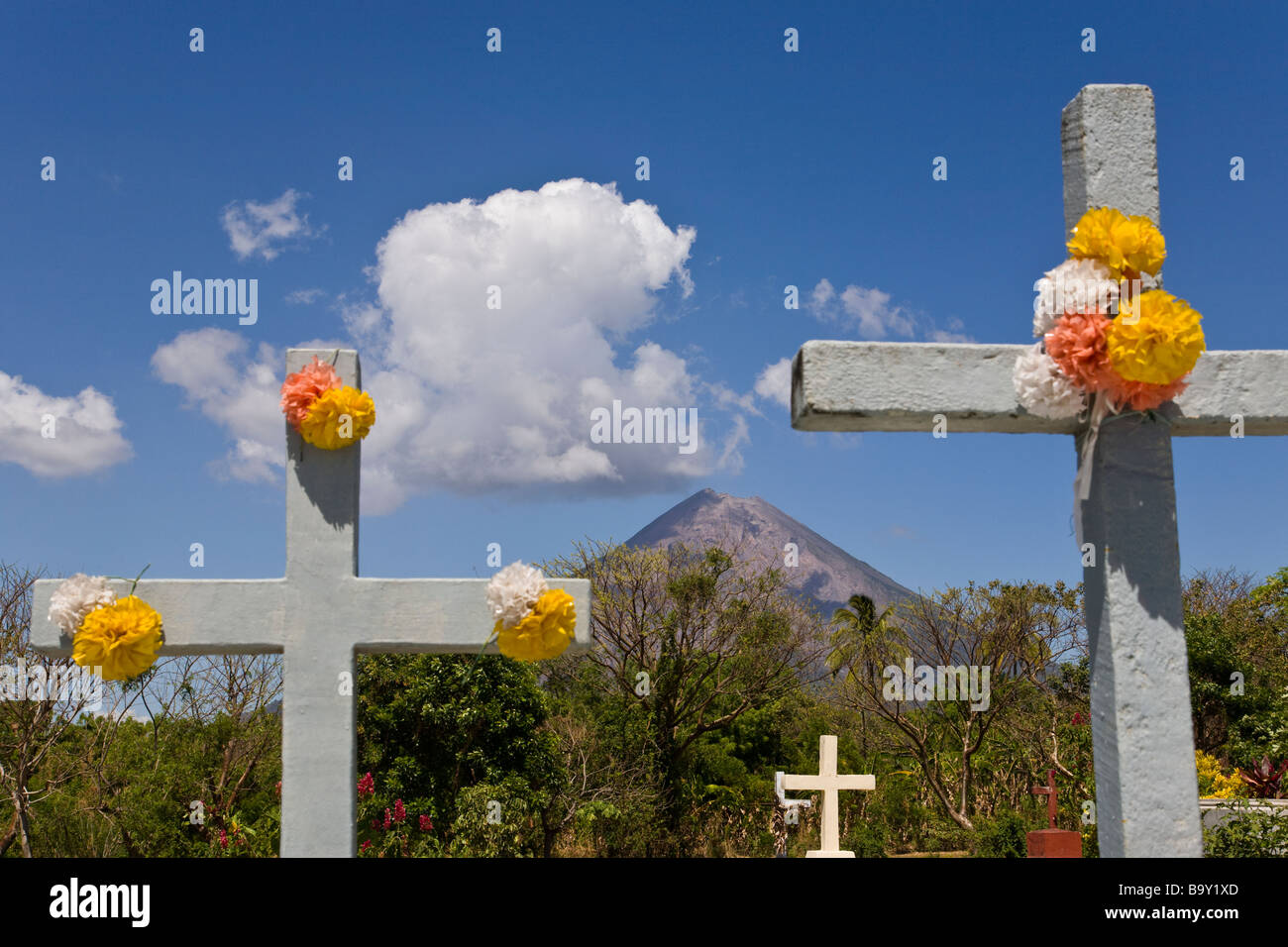 Blumengeschmückten Kreuze markieren die Gräber der Cementerio Los Angeles in Moyogalpa, Nicaragua auf der Insel Ometepe mit Volcan Concepcion hinter droht. Stockfoto