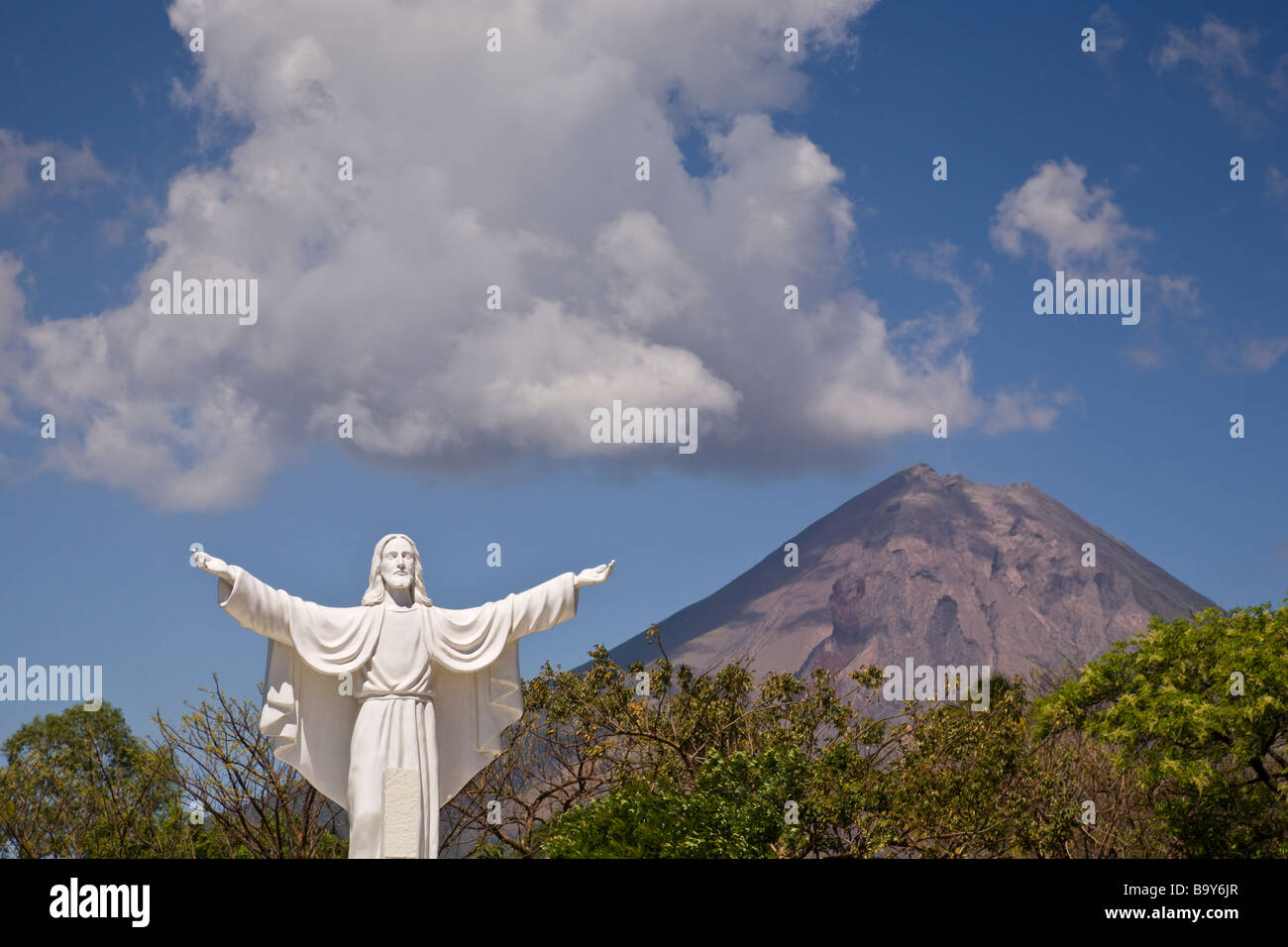 Statue von Jesus an der Cementerio Los Angeles in Moyogalpa, Nicaragua auf der Insel Ometepe mit der Volcan Concepcion hinter droht. Stockfoto